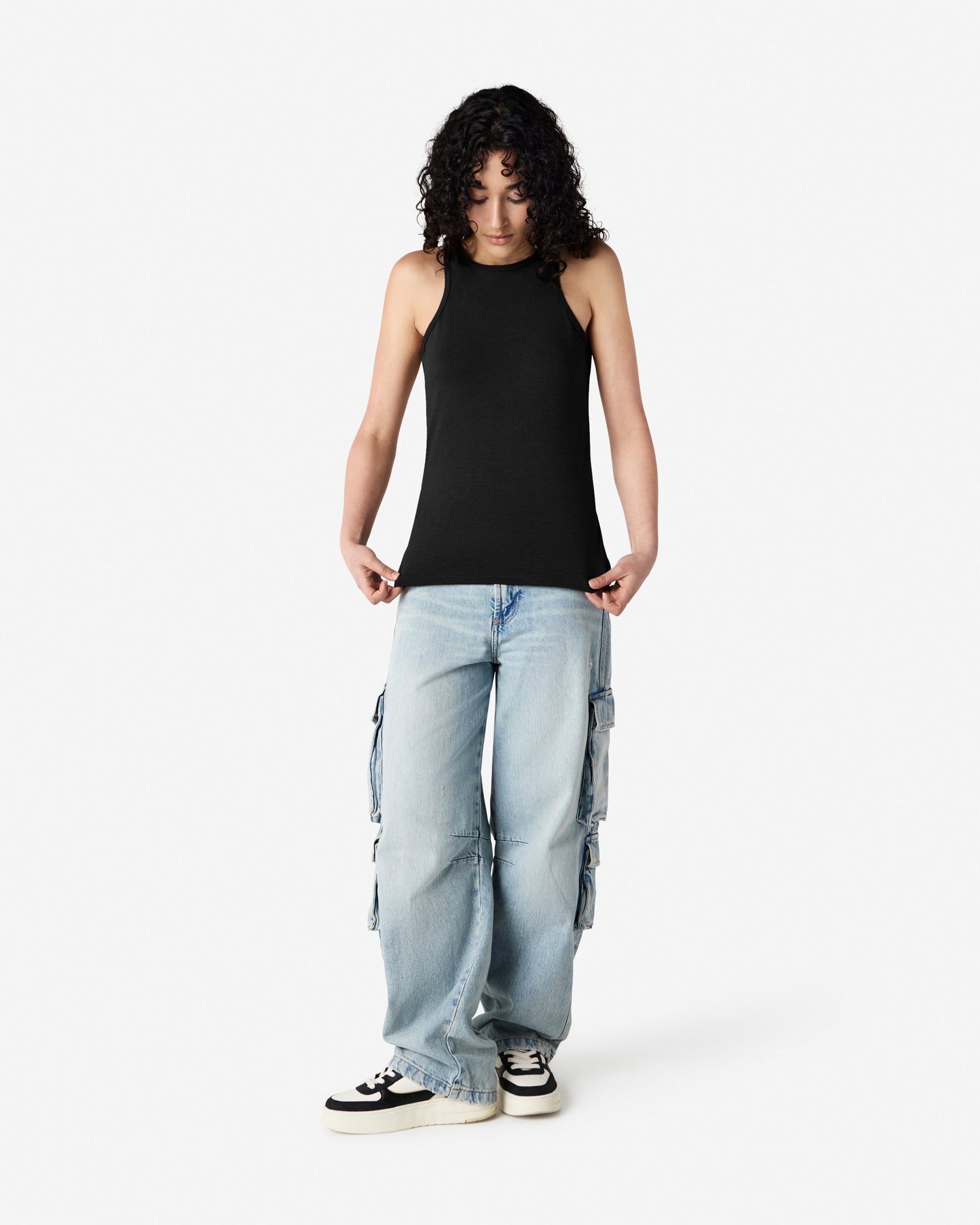 Woman dressed in a American Apparel Racerneck tank top and light-wash cargo jeans, styled casually with sneakers against a white background - black