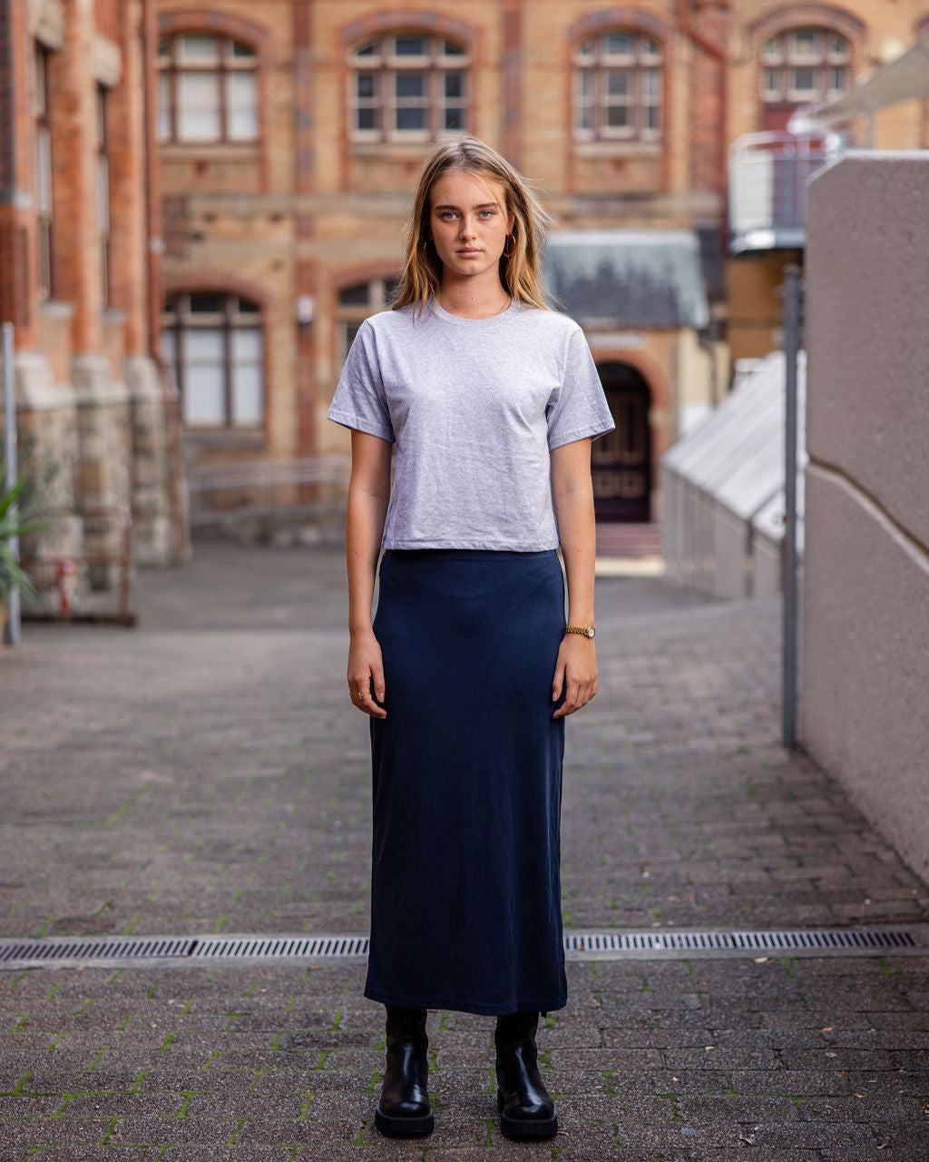 Female model wearing an American Apparel Fine Jersey Women's Boxy Tee in Cream, paired with blue jeans, standing against a plain background (front pose) - Heather Grey