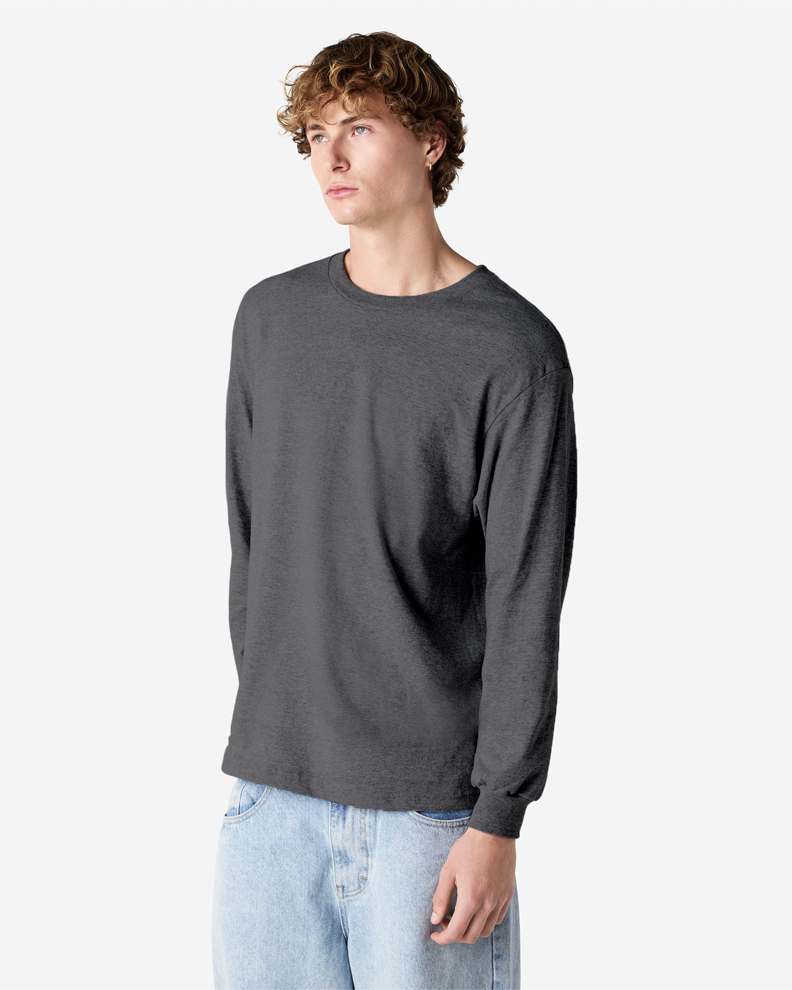 front view of a male Model wearing a Heather Charcoal colored Heavyweight Unisex Long Sleeve Crew Neck Tee, paired with blue jeans, standing against a plain background (front pose) -heather charcoal
