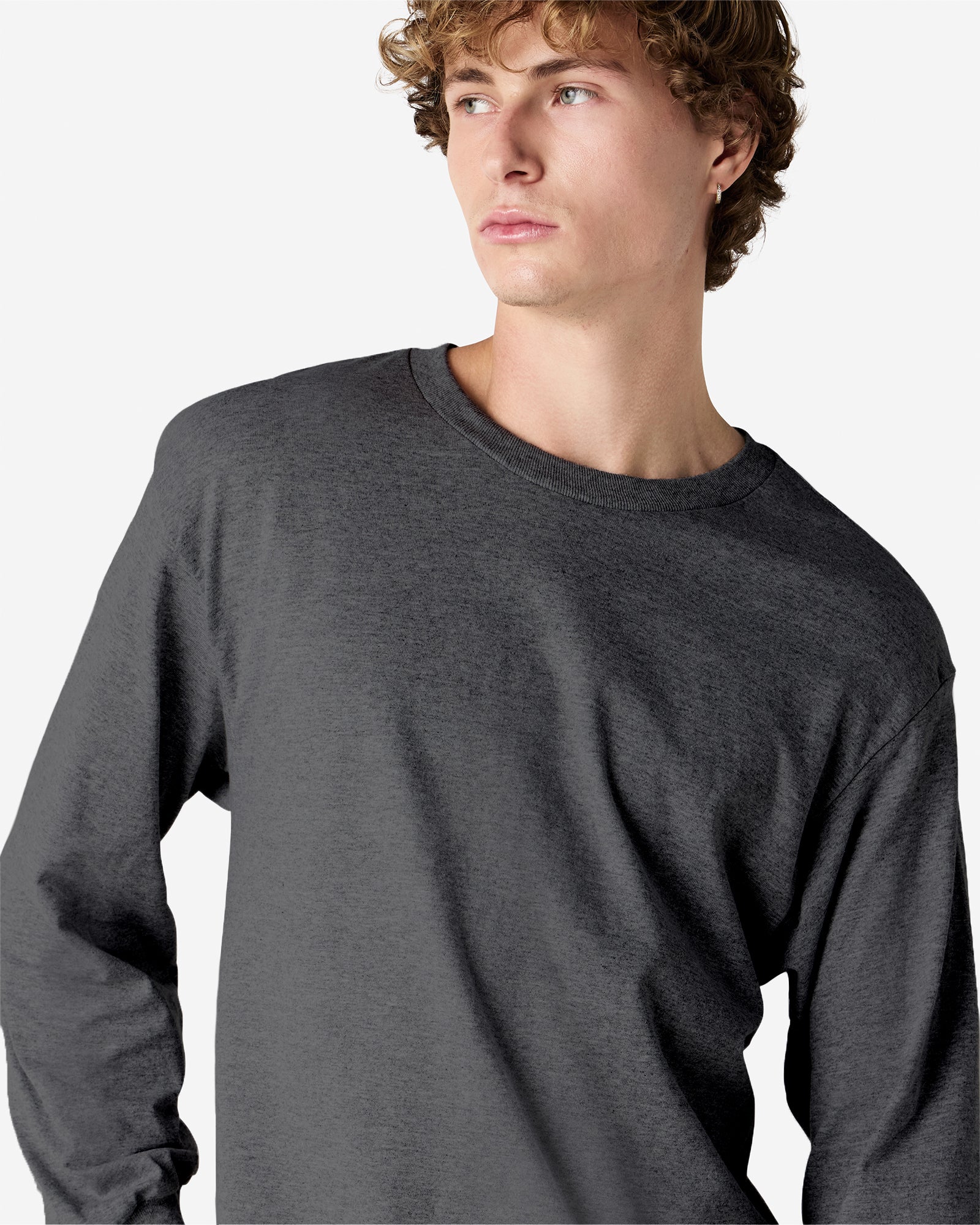 front view of a male Model wearing a Heather Charcoal colored Heavyweight Unisex Long Sleeve Crew Neck Tee, paired with blue jeans, standing against a plain background (front pose) -heather charcoal