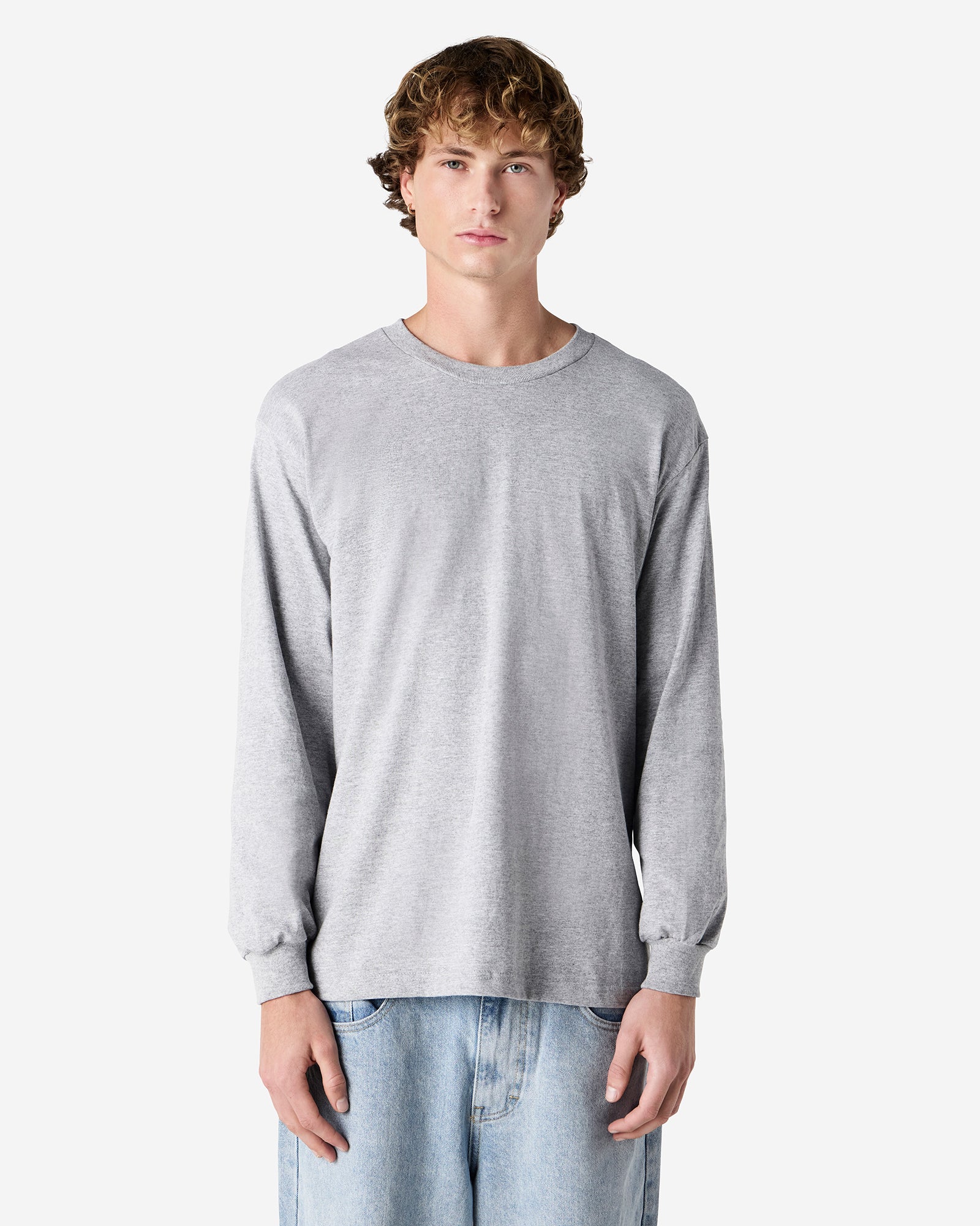 front view of a male Model wearing a Heather Charcoal Grey Heavyweight Unisex Long Sleeve Crew Neck Tee, paired with blue jeans, standing against a plain background (front pose) -heather Grey