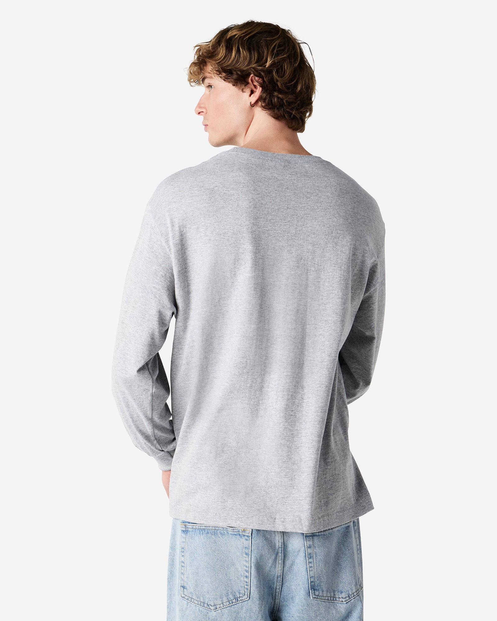 front view of a male Model wearing a Heather Charcoal Grey Heavyweight Unisex Long Sleeve Crew Neck Tee, paired with blue jeans, standing against a plain background (front pose) -heather Grey