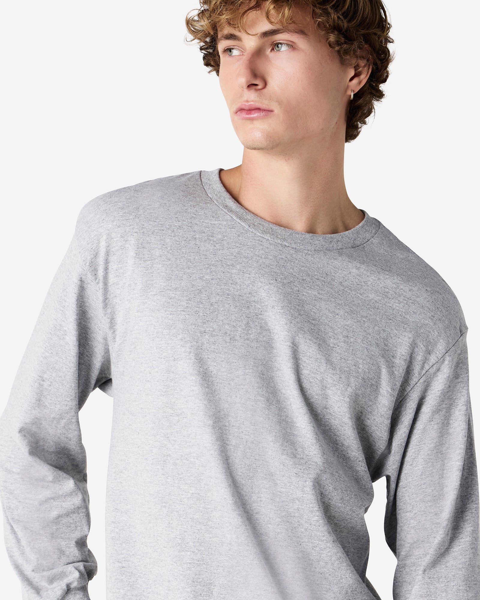 front view of a male Model wearing a Heather Charcoal Grey Heavyweight Unisex Long Sleeve Crew Neck Tee, paired with blue jeans, standing against a plain background (front pose) -heather Grey