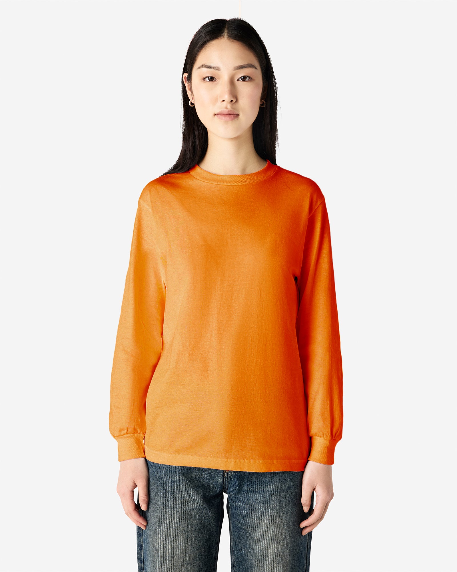 front view of a female Model wearing a Heather Orange Heavyweight Unisex Long Sleeve Crew Neck Tee, paired with blue jeans, standing against a plain background (front pose) -orange
