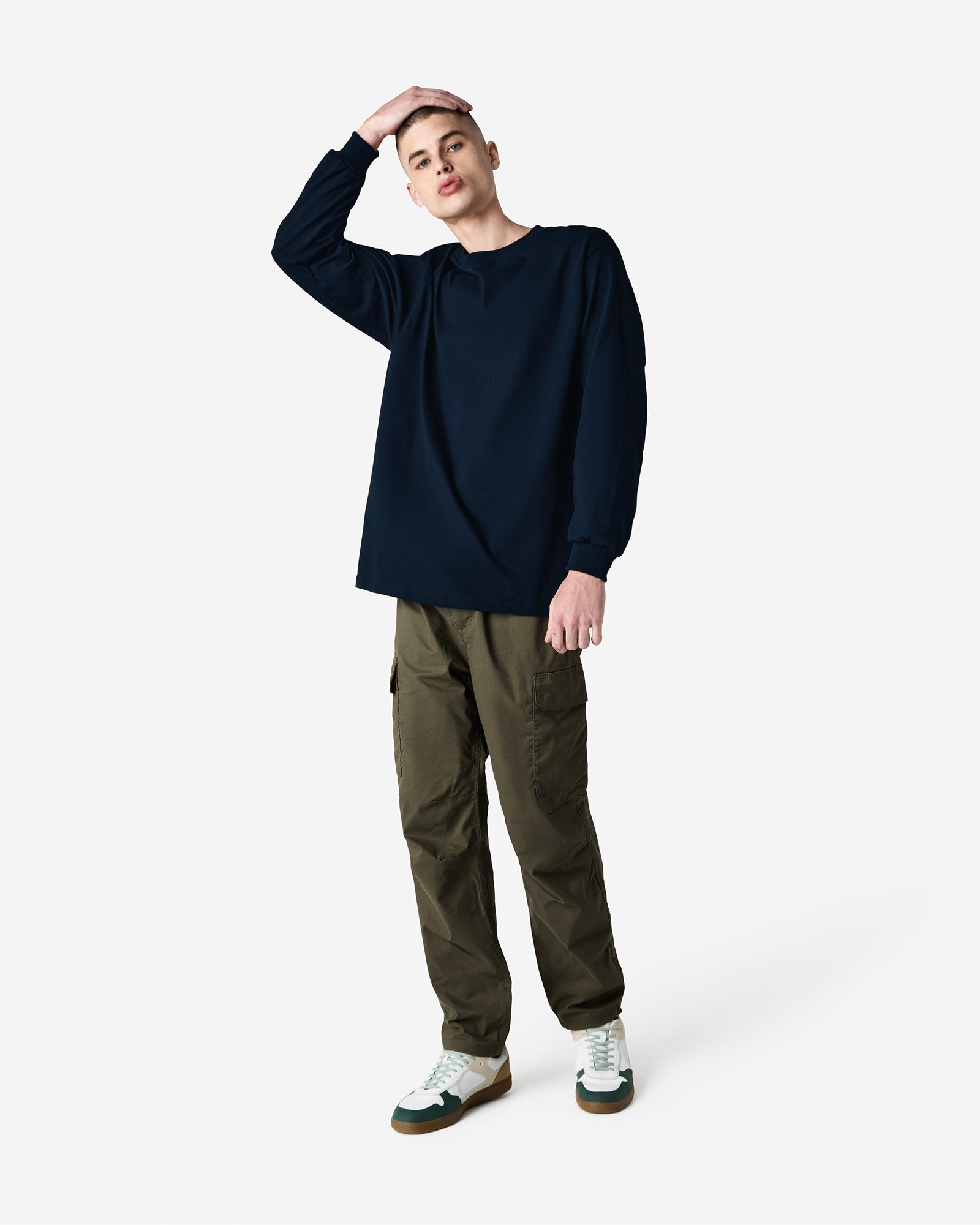 front view of a male Model wearing a True Navy colored Heavyweight Unisex Long Sleeve Crew Neck Tee, paired with blue jeans, standing against a plain background (front pose) -true navy