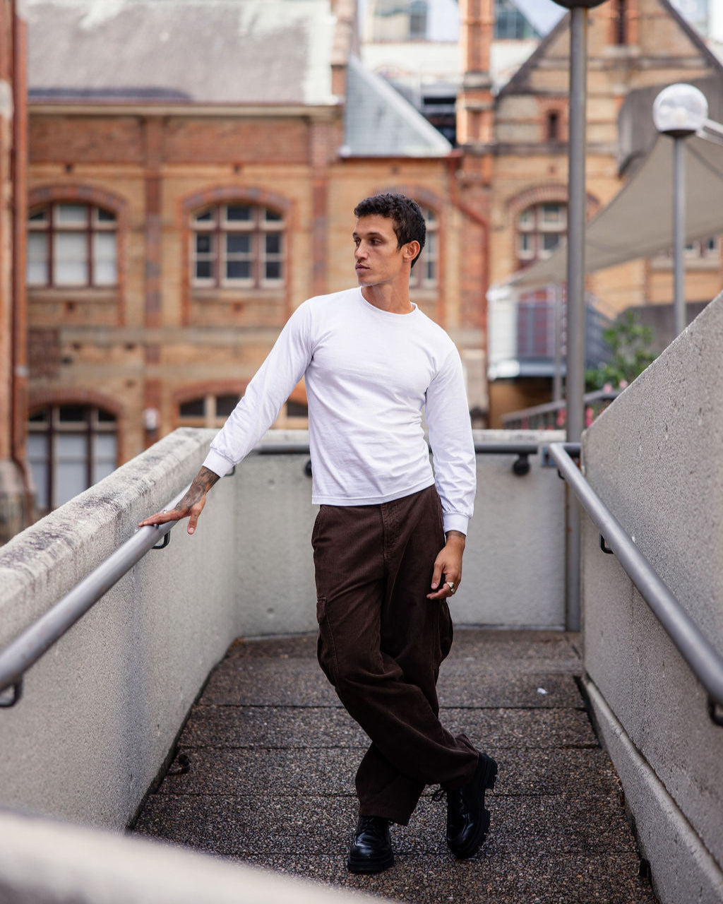 front view of a female Model wearing a White colored Heavyweight Unisex Long Sleeve Crew Neck Tee, paired with blue jeans, standing against a plain background (front pose) -white