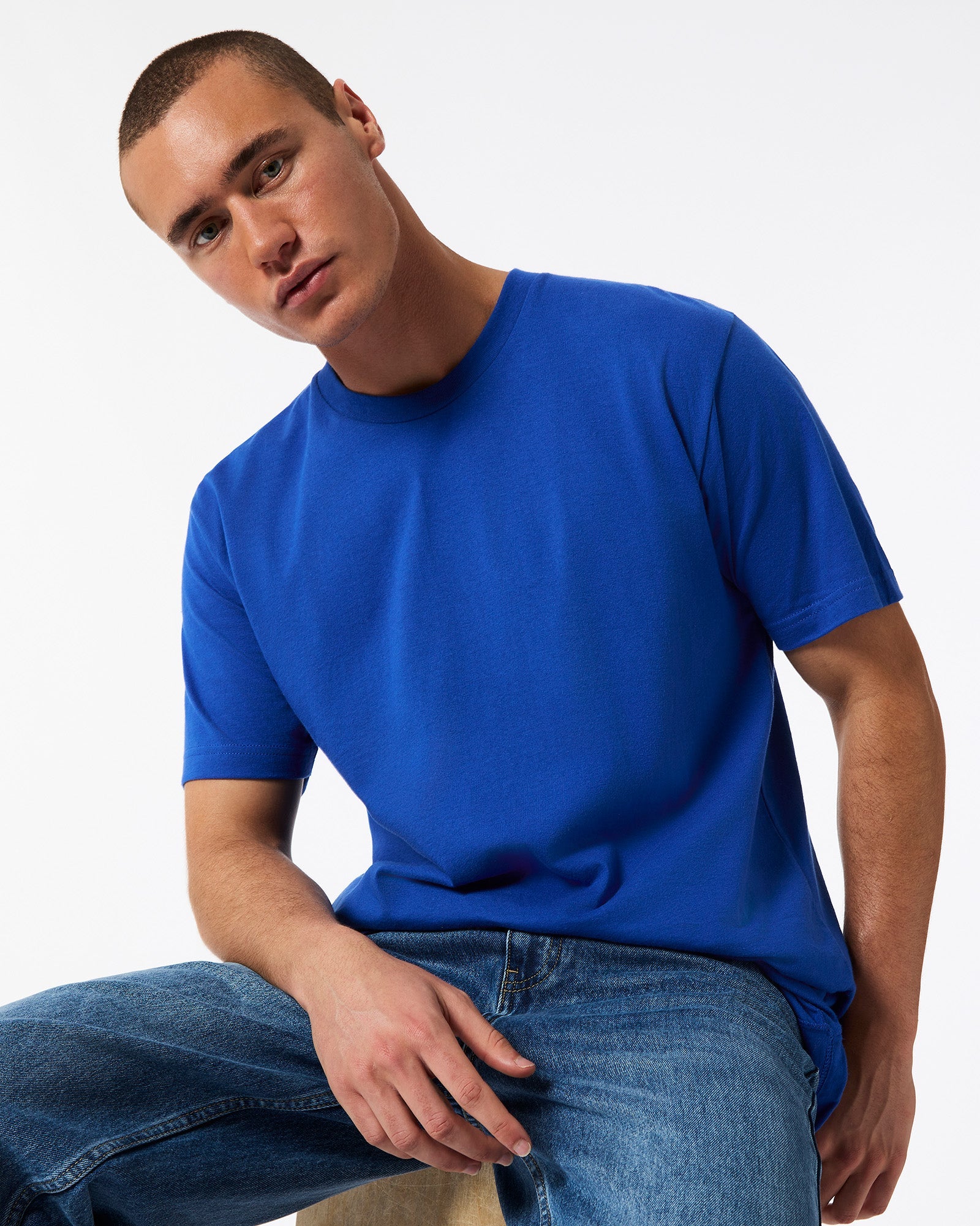 Male model wearing American Apparel Powder Royal Blue Colour Fine Jersey Unisex Short Sleeve Crew Neck Tee (sitting front pose) -royal blue