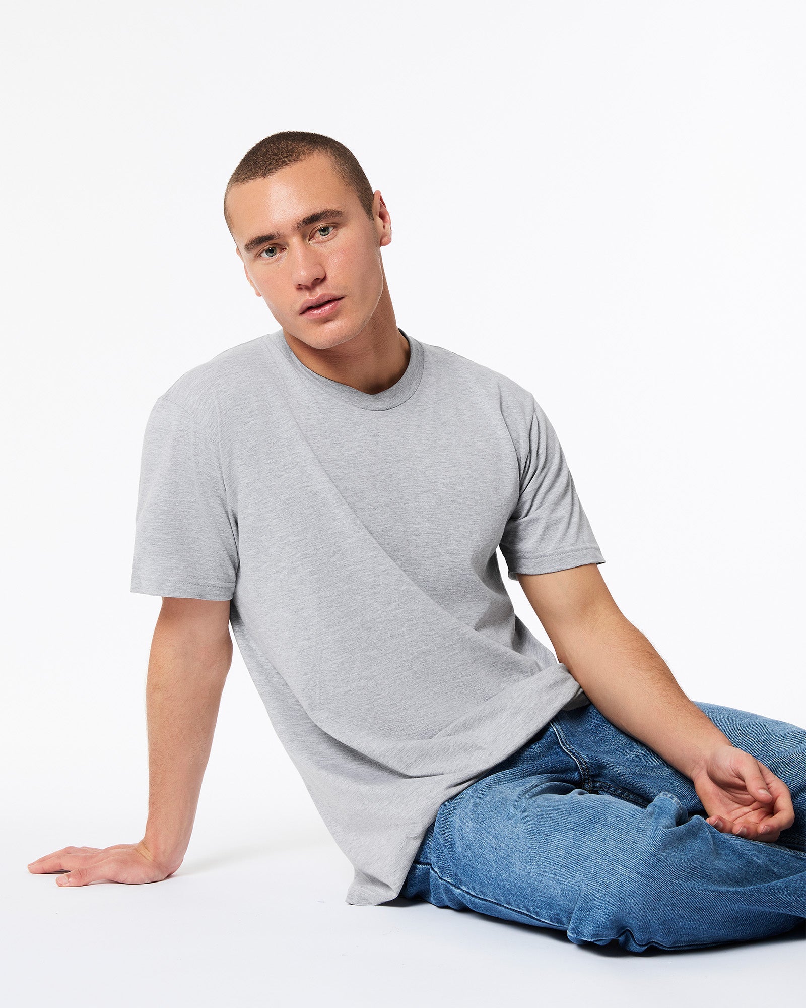 male model wearing heather grey colour Fine Jersey Unisex Crew Neck Tee (sitting pose) -heather grey