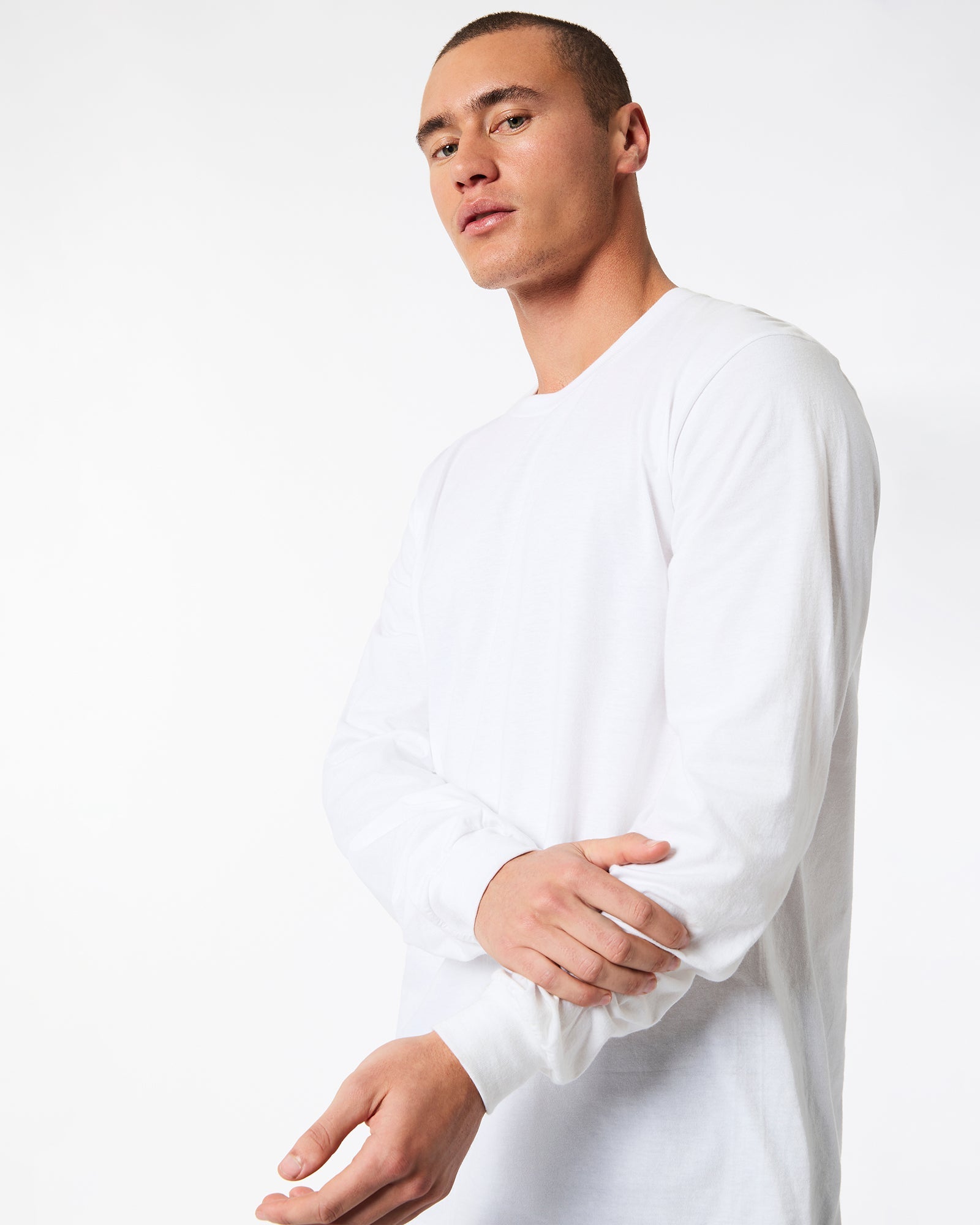 male model wearing American Apparel white Colour Fine Jersey Unisex Long Sleeve Crew Neck Tee (hand on wrist Front pose) -white