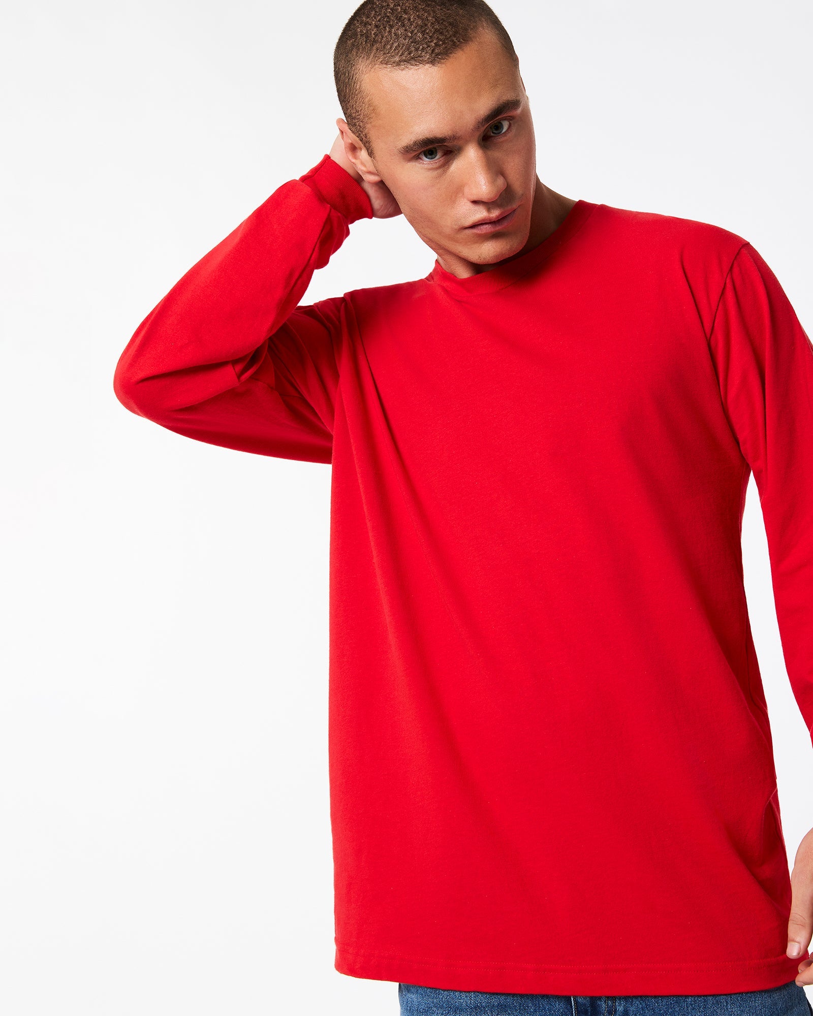 male model wearing American Apparel Red Colour Fine Jersey Unisex Long Sleeve Crew Neck Tee (hand behind head pose) -red