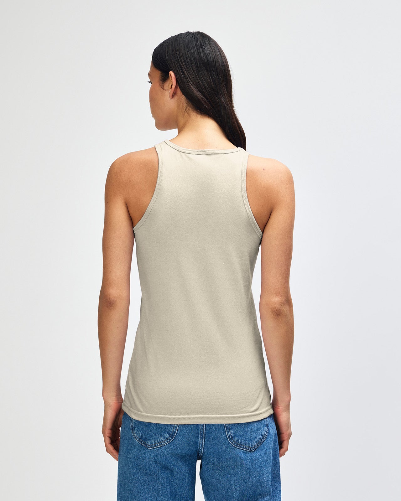 Front-facing view of a woman wearing the American Apparel Racerneck tank top, paired with light blue denim for a clean, minimalist look - heather bone
