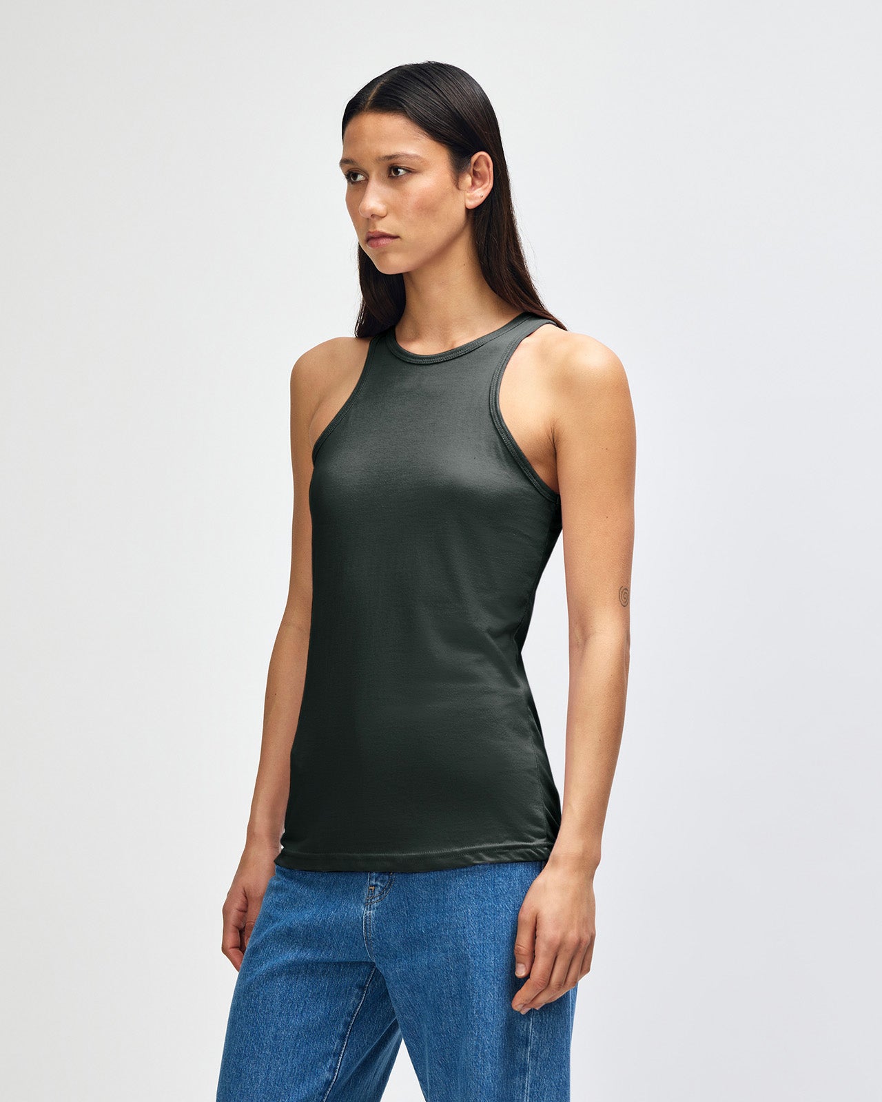 Front-facing view of a woman wearing the American Apparel Racerneck tank top, paired with light blue denim for a clean, minimalist look - heather charcoal