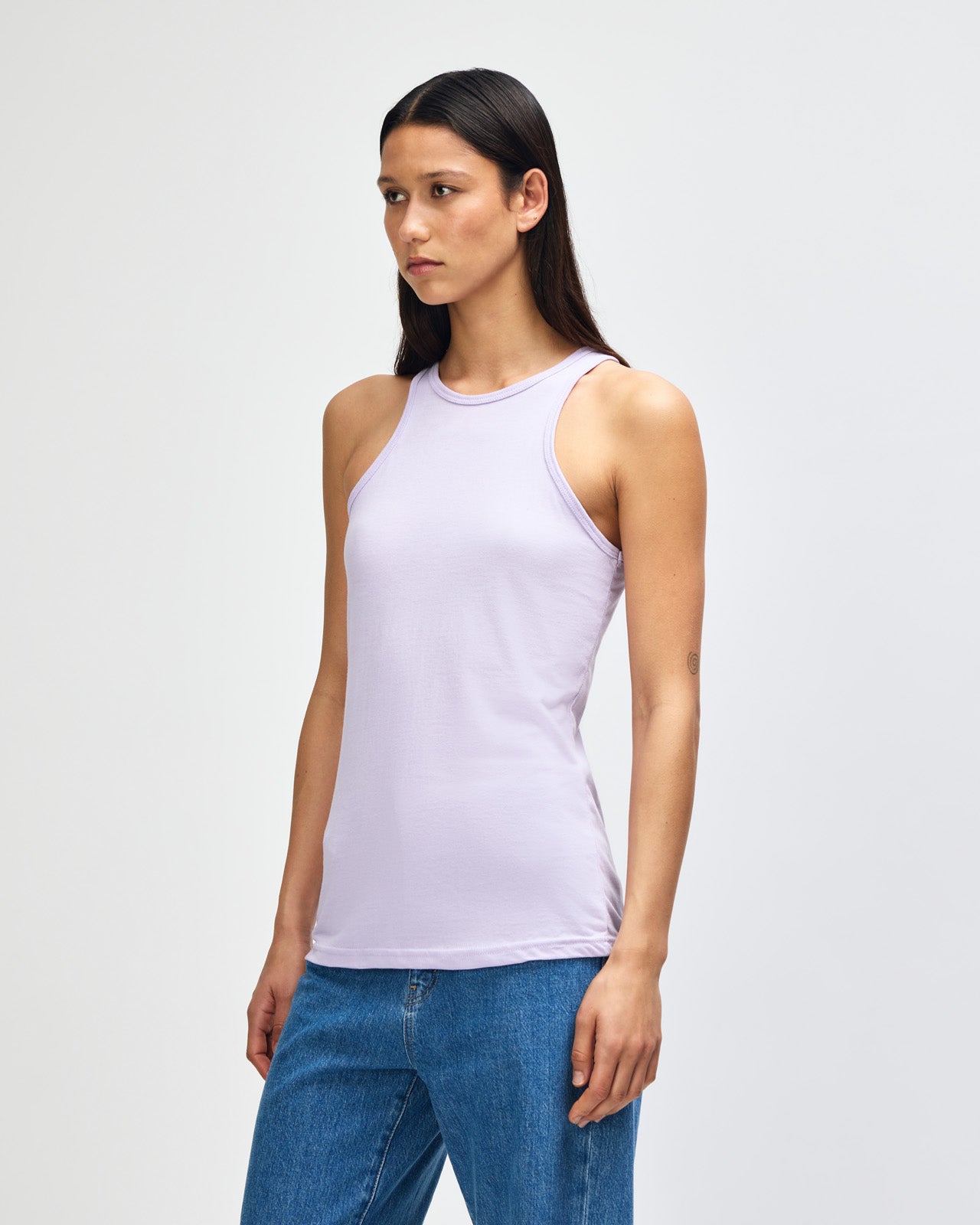 Front-facing view of a woman wearing the American Apparel Racerneck tank top, paired with light blue denim for a clean, minimalist look - lilac