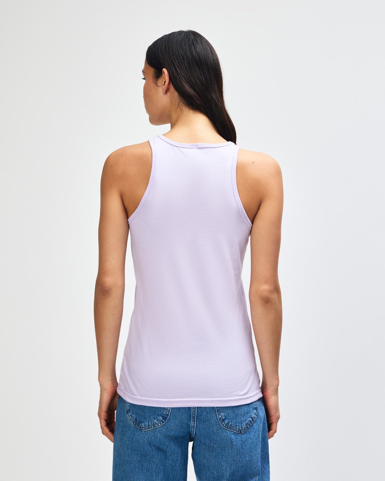 Front-facing view of a woman wearing the American Apparel Racerneck tank top, paired with light blue denim for a clean, minimalist look - lilac