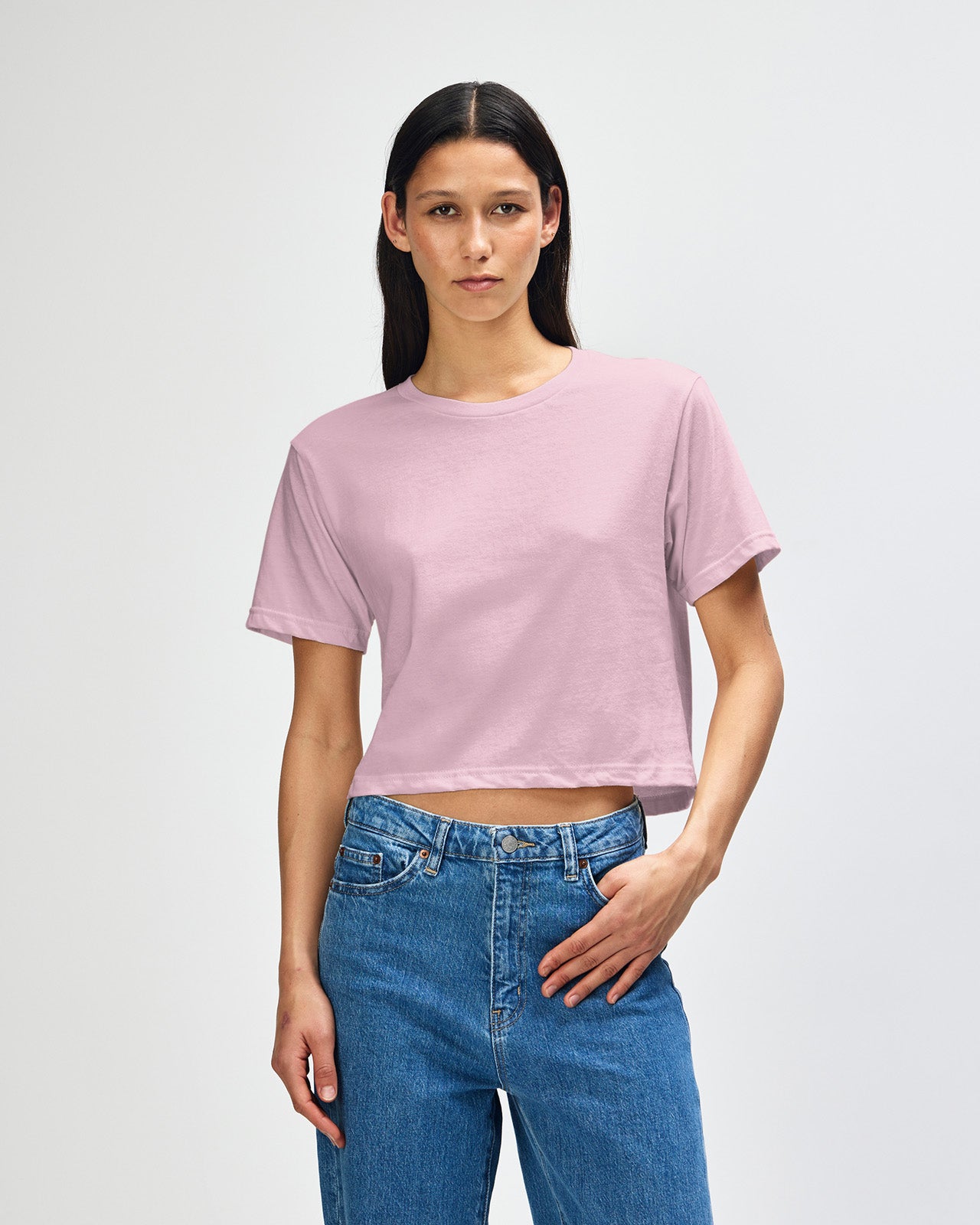 Female model wearing an American Apparel Fine Jersey Women's Boxy Tee in Black, paired with blue jeans, standing against a plain background (front pose) -blush