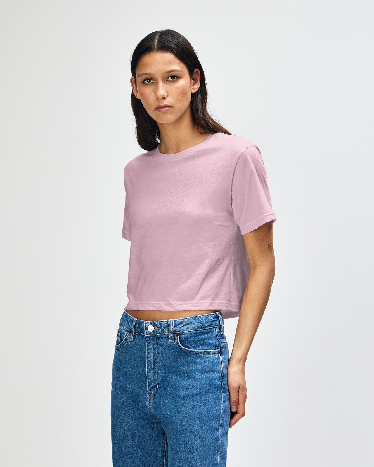 Female model wearing an American Apparel Fine Jersey Women's Boxy Tee in Black, paired with blue jeans, standing against a plain background (front pose) -blush