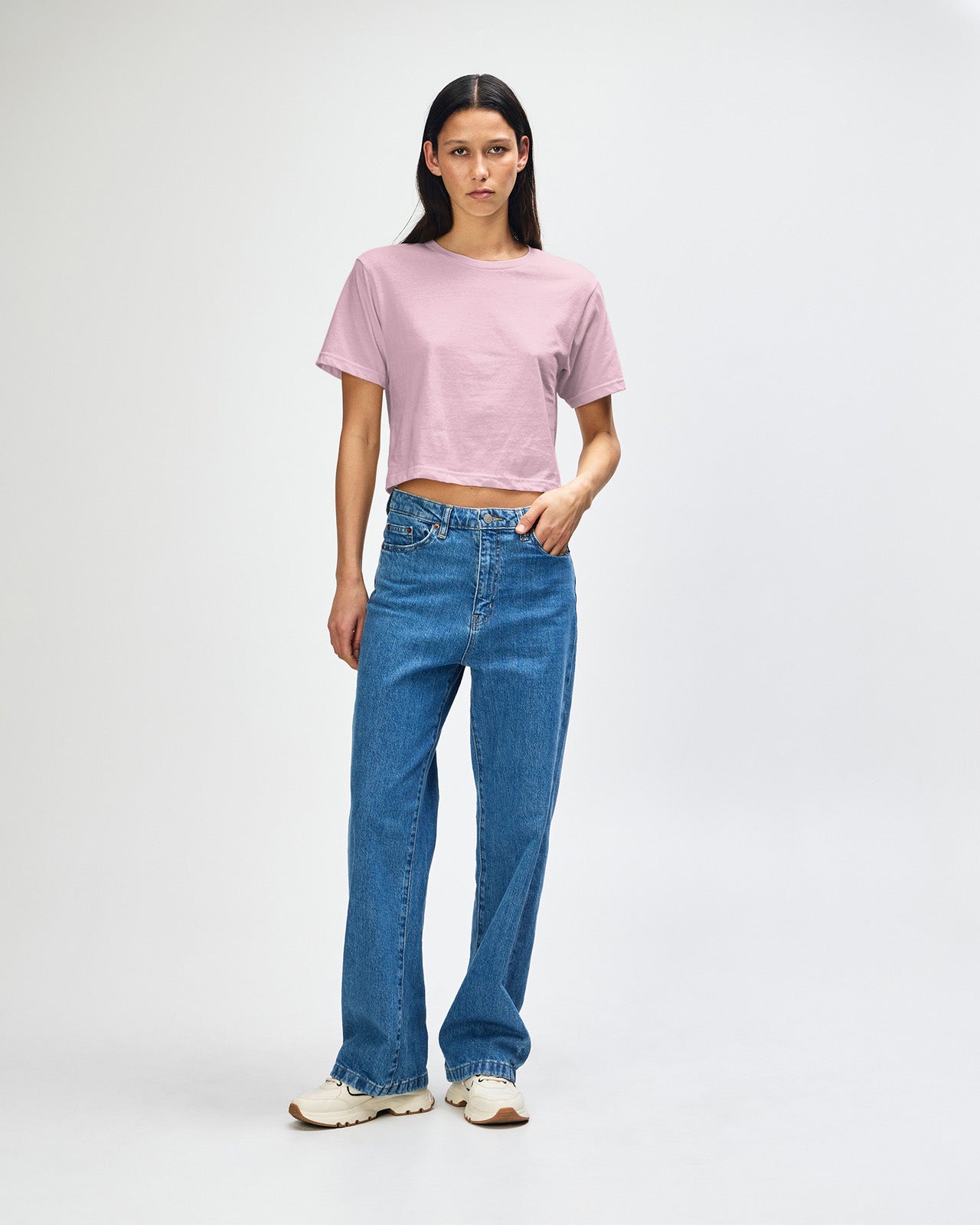 Female model wearing an American Apparel Fine Jersey Women's Boxy Tee in Black, paired with blue jeans, standing against a plain background (front pose) -blush