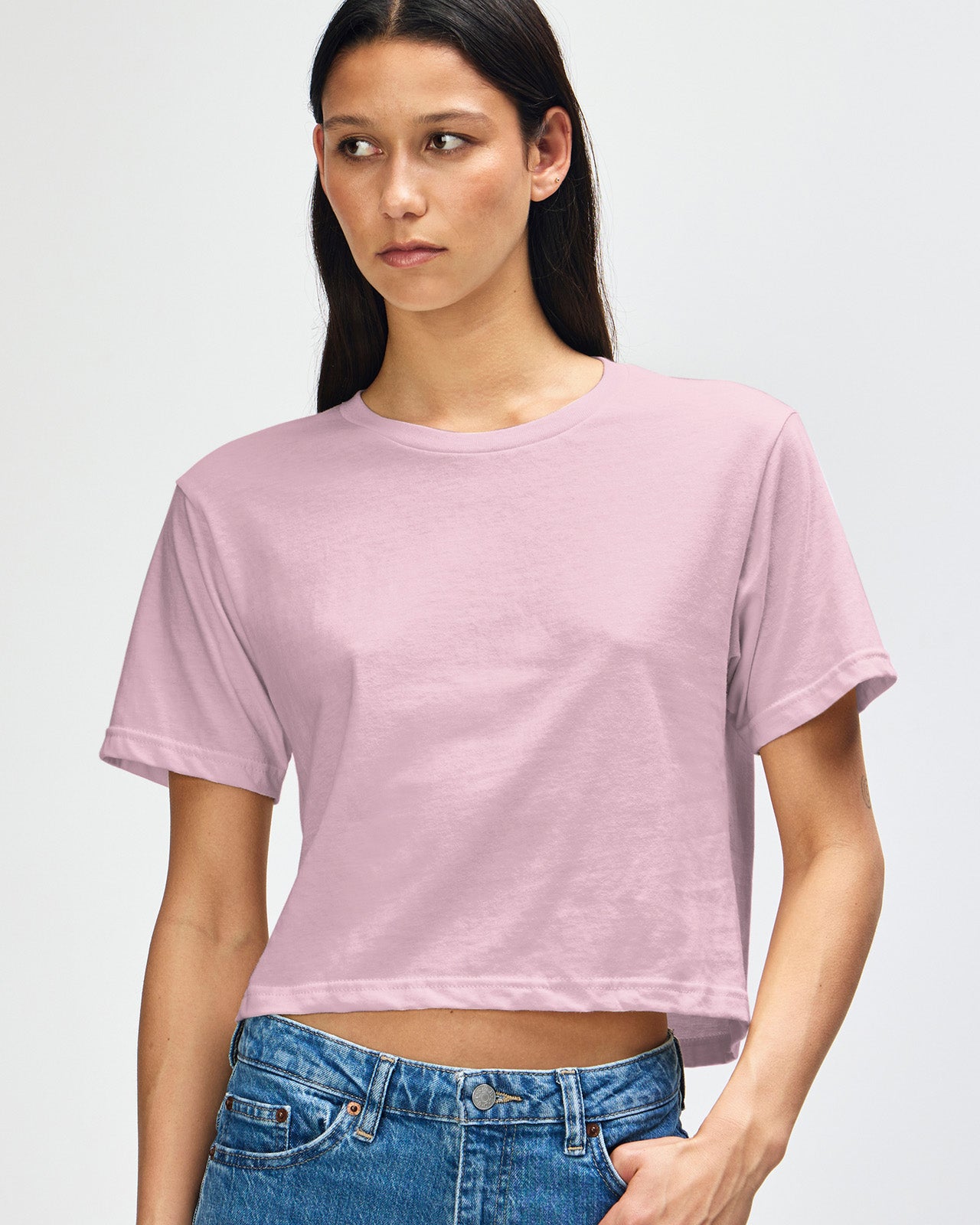 Female model wearing an American Apparel Fine Jersey Women's Boxy Tee in Black, paired with blue jeans, standing against a plain background (front pose) -blush