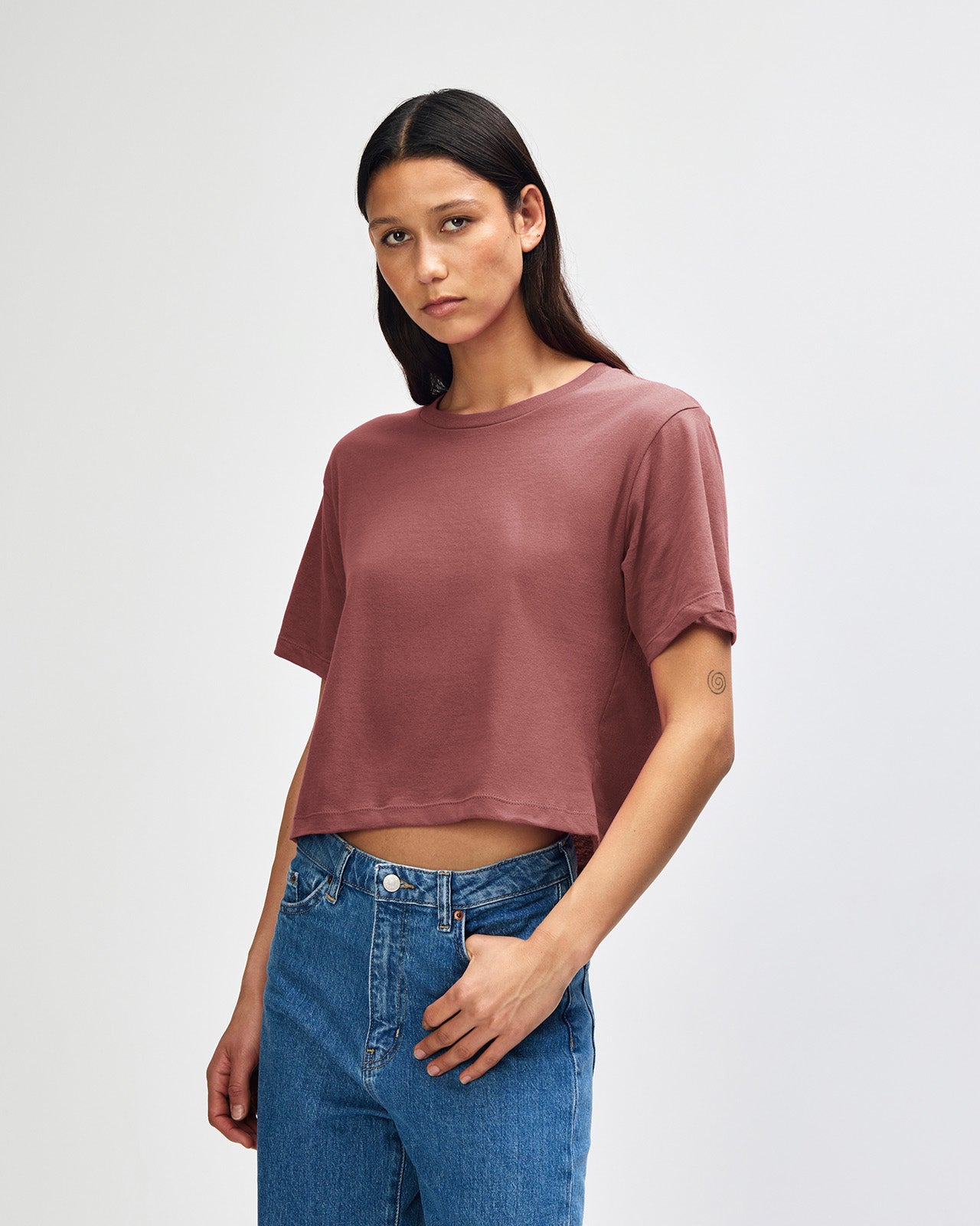Female model wearing an American Apparel Fine Jersey Women's Boxy Tee in canyon, paired with blue jeans, standing against a plain background (front pose) -canyon