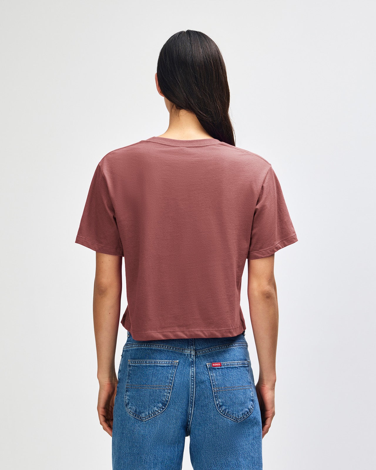 Female model wearing an American Apparel Fine Jersey Women's Boxy Tee in canyon, paired with blue jeans, standing against a plain background (front pose) -canyon