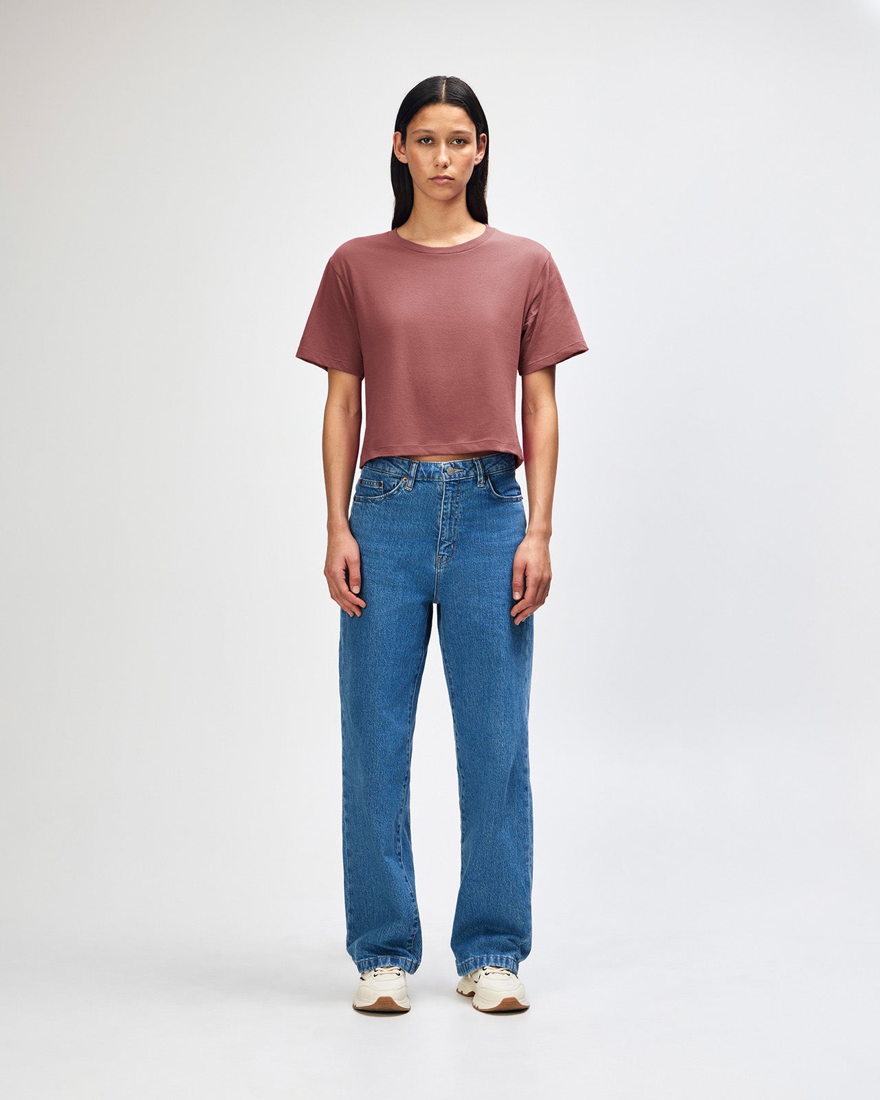 Female model wearing an American Apparel Fine Jersey Women's Boxy Tee in canyon, paired with blue jeans, standing against a plain background (front pose) -canyon