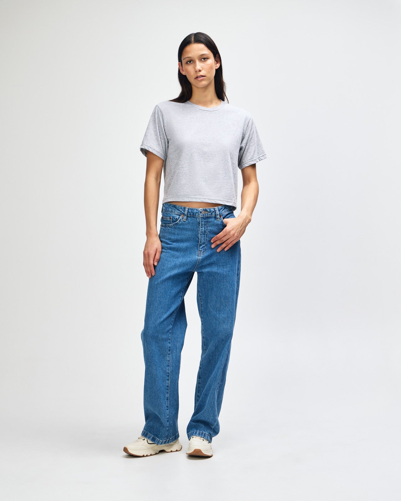 Female model wearing an American Apparel Fine Jersey Women's Boxy Tee in Heather Sport Grey, paired with black jeans, standing against a plain background (front pose) -heather grey