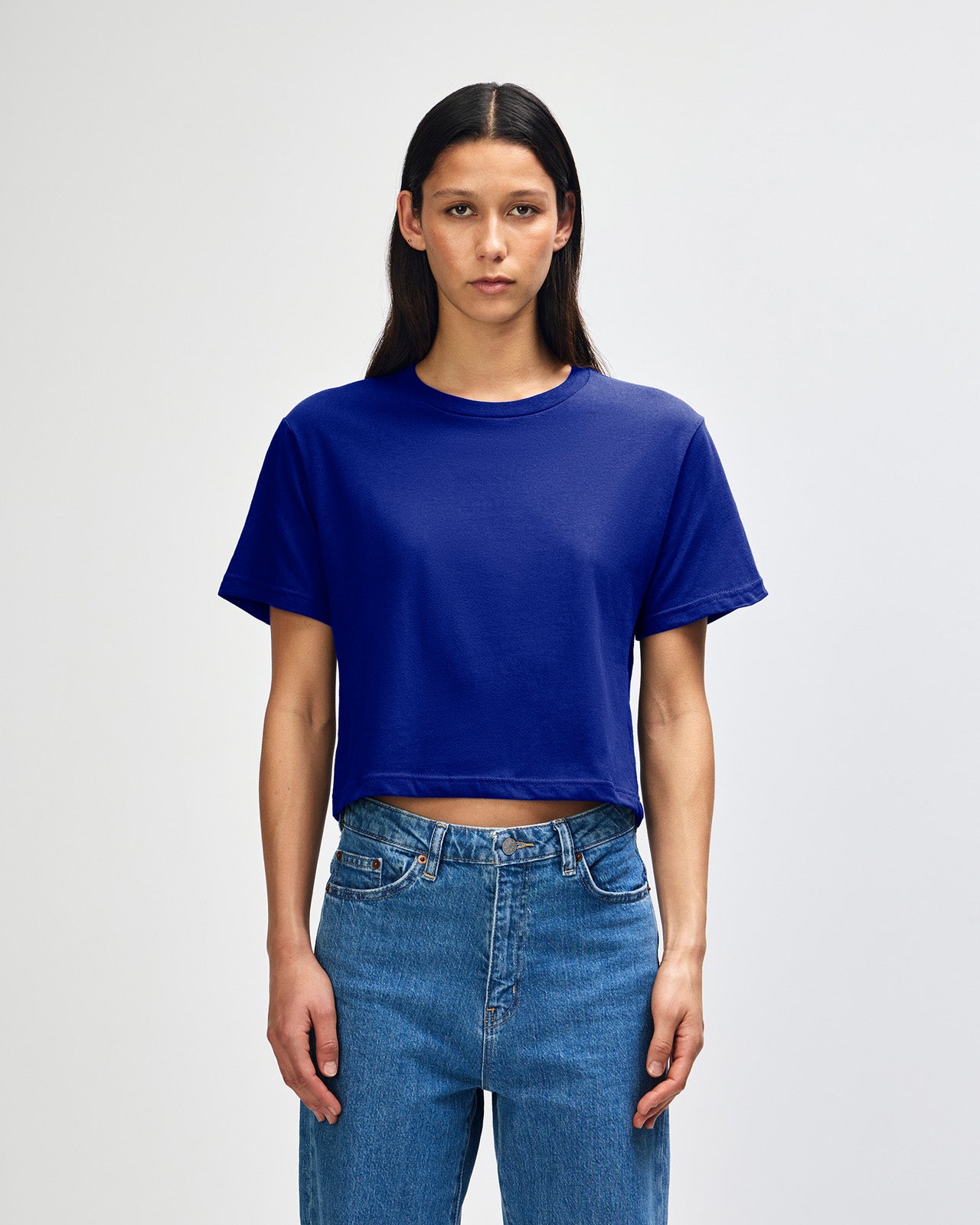Female model wearing an American Apparel Fine Jersey Women's Boxy Tee in Lapis, paired with blue jeans, standing against a plain background (front pose) -lapis