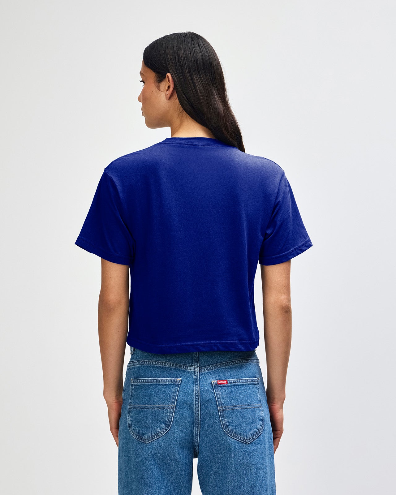Female model wearing an American Apparel Fine Jersey Women's Boxy Tee in Lapis, paired with blue jeans, standing against a plain background (front pose) -lapis