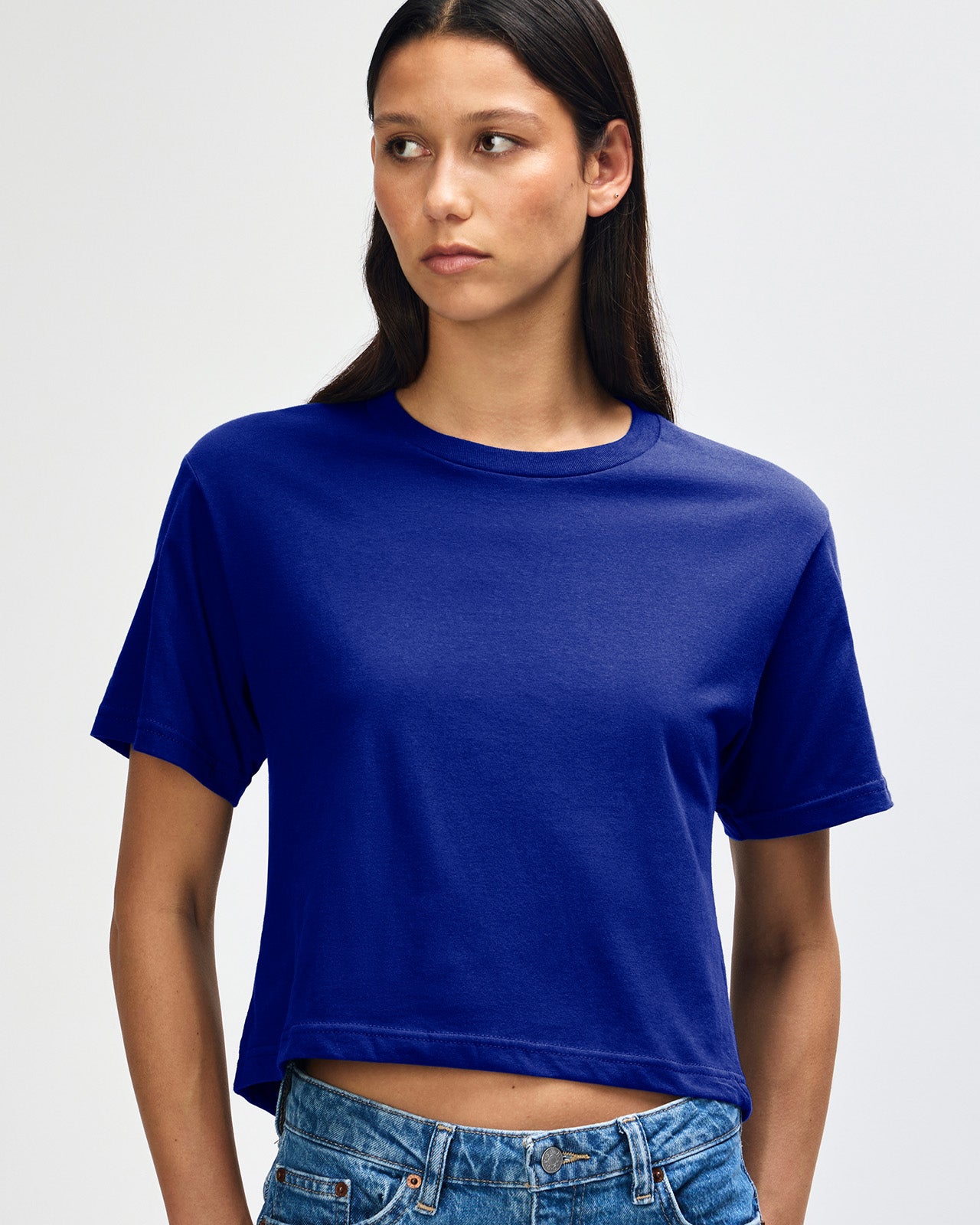 Female model wearing an American Apparel Fine Jersey Women's Boxy Tee in Lapis, paired with blue jeans, standing against a plain background (front pose) -lapis