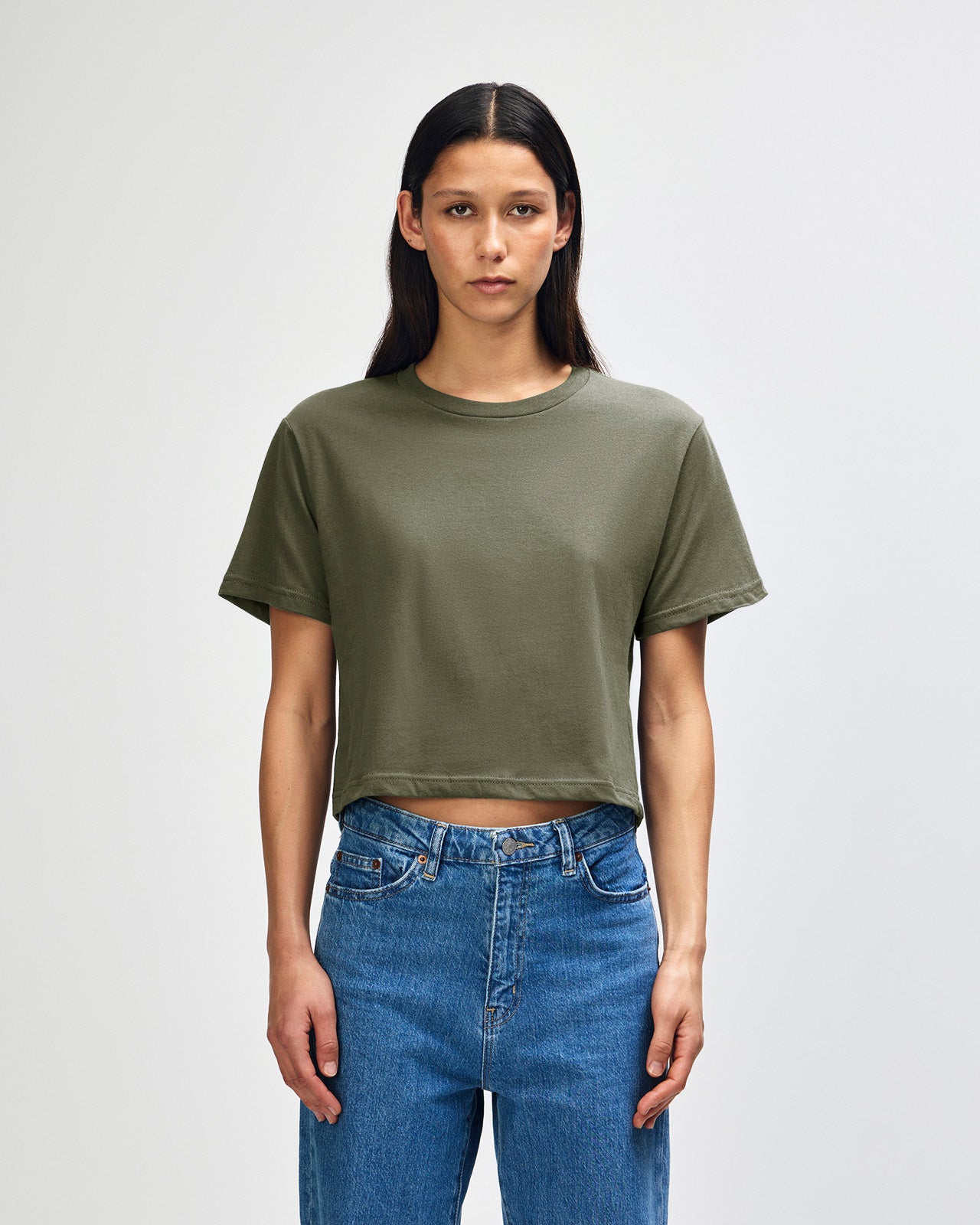 Female model wearing an American Apparel Fine Jersey Women's Boxy Tee in Lieutenant, paired with blue jeans, standing against a plain background (front pose) -lieutenant
