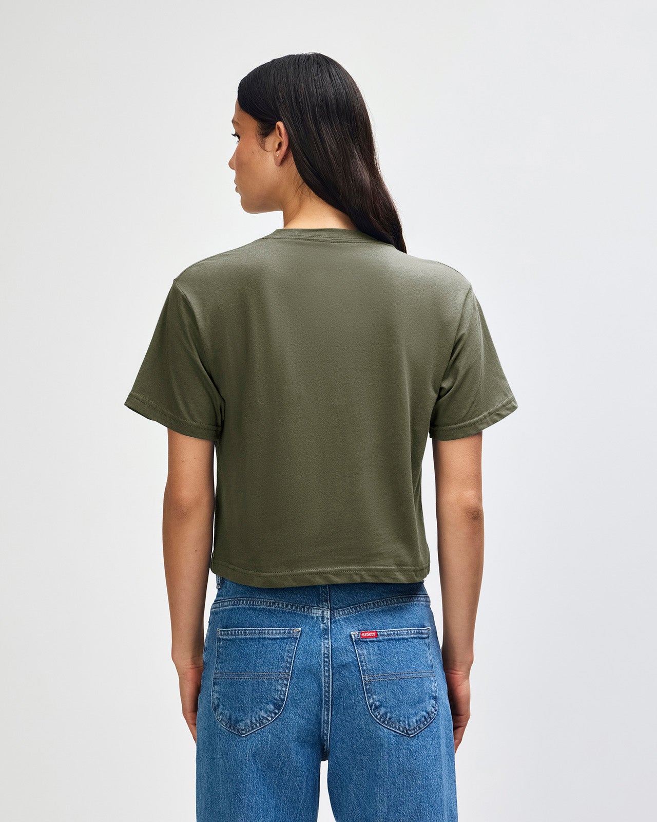 Female model wearing an American Apparel Fine Jersey Women's Boxy Tee in Lieutenant, paired with blue jeans, standing against a plain background (front pose) -lieutenant