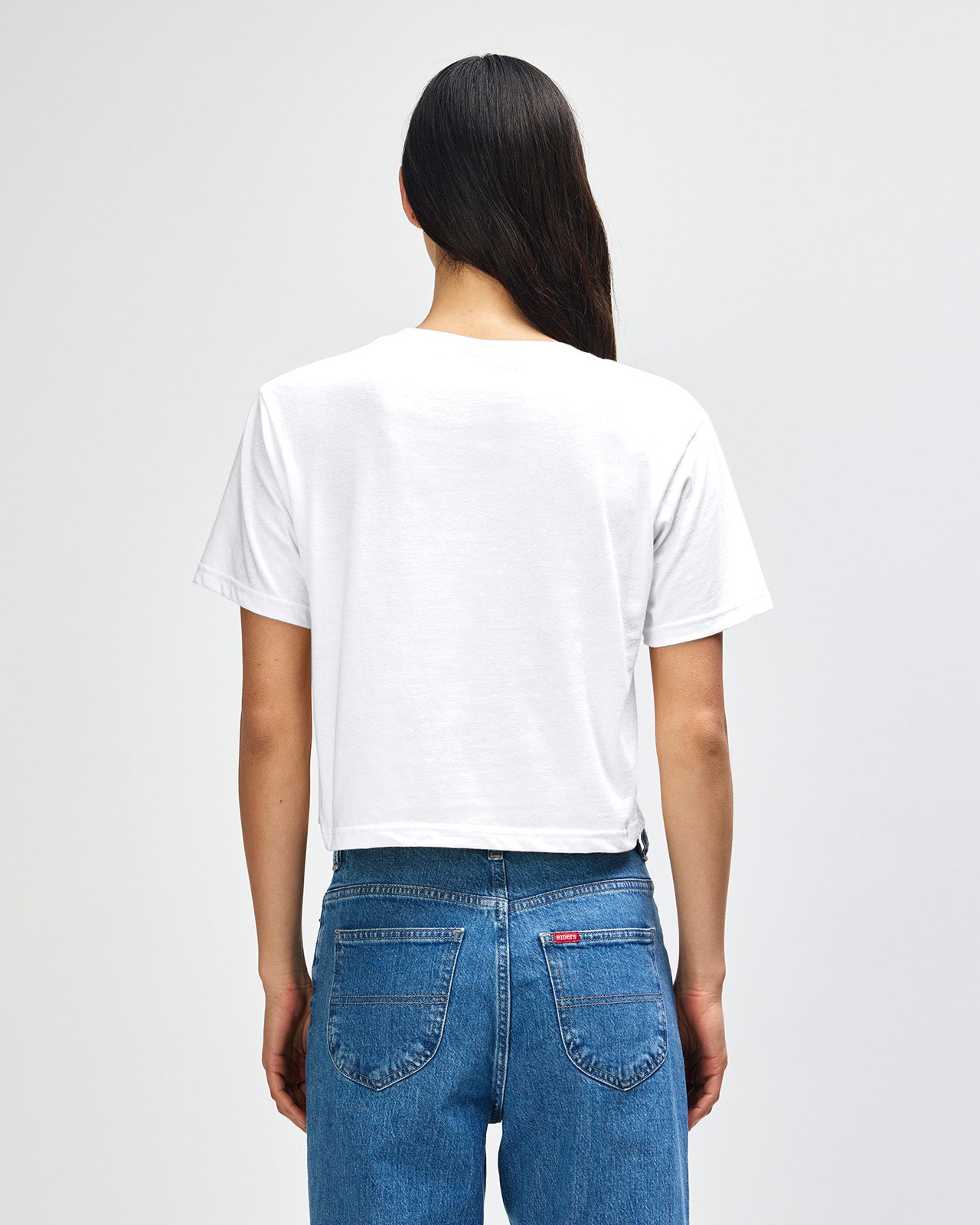 Female model wearing an American Apparel Fine Jersey Women's Boxy Tee in white, paired with blue jeans, standing against a plain background (front pose) -white