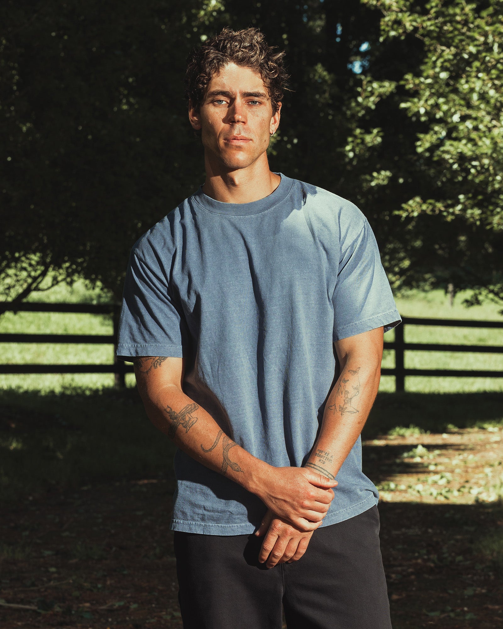 Male model wearing an American Apparel Garment Dyed Heavyweight Cotton Tee Shirt in Faded Navy, paired with light blue jeans, standing against a plain background (front pose) -Navy