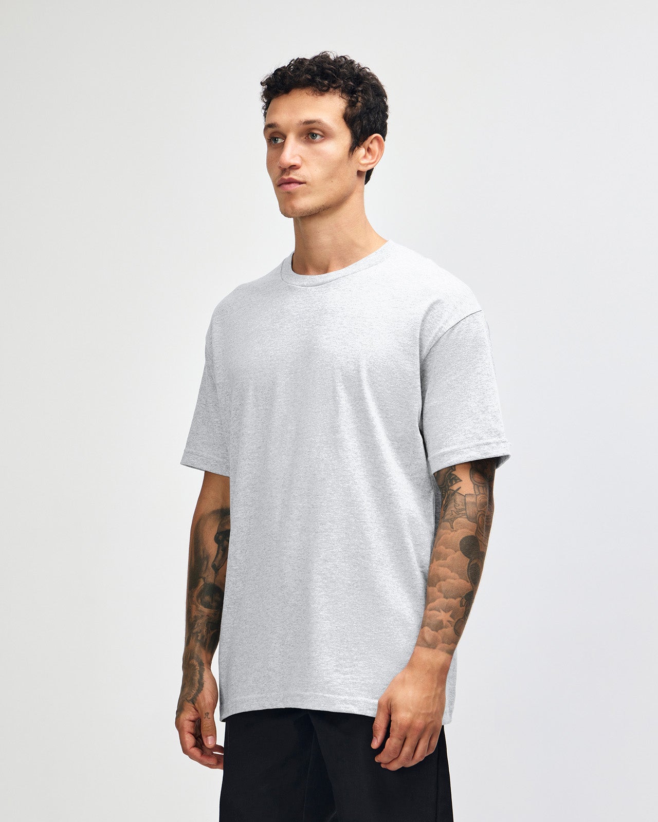 Male Model wearing a Ash Heavyweight Unisex Short Sleeve Crew Neck Tee, paired with green cargo pants standing against a plain background (front pose) -ash