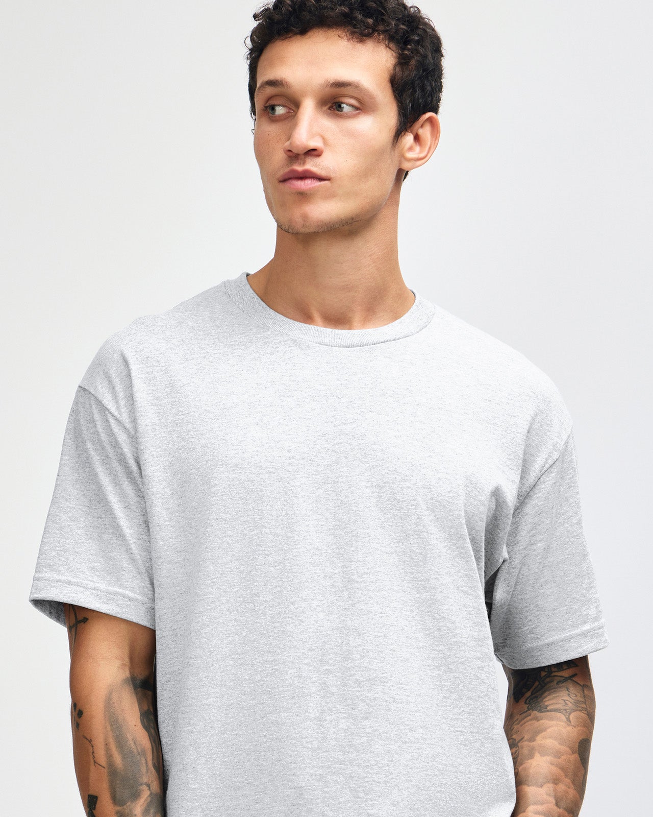 Male Model wearing a Ash Heavyweight Unisex Short Sleeve Crew Neck Tee, paired with green cargo pants standing against a plain background (front pose) -ash