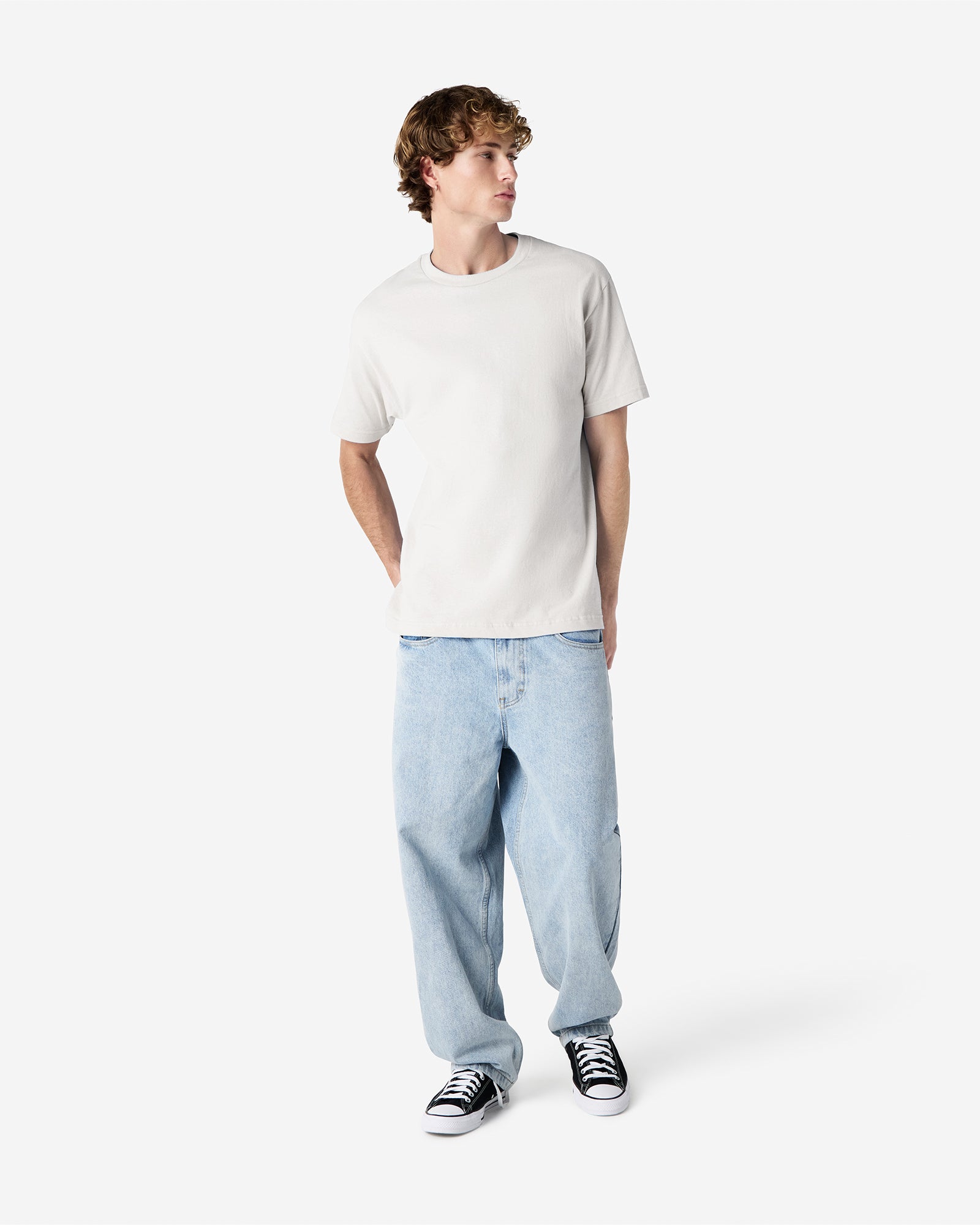 Male Model wearing a Ash Heavyweight Unisex Short Sleeve Crew Neck Tee, paired with blue jeans, standing against a plain background (front pose) -ash