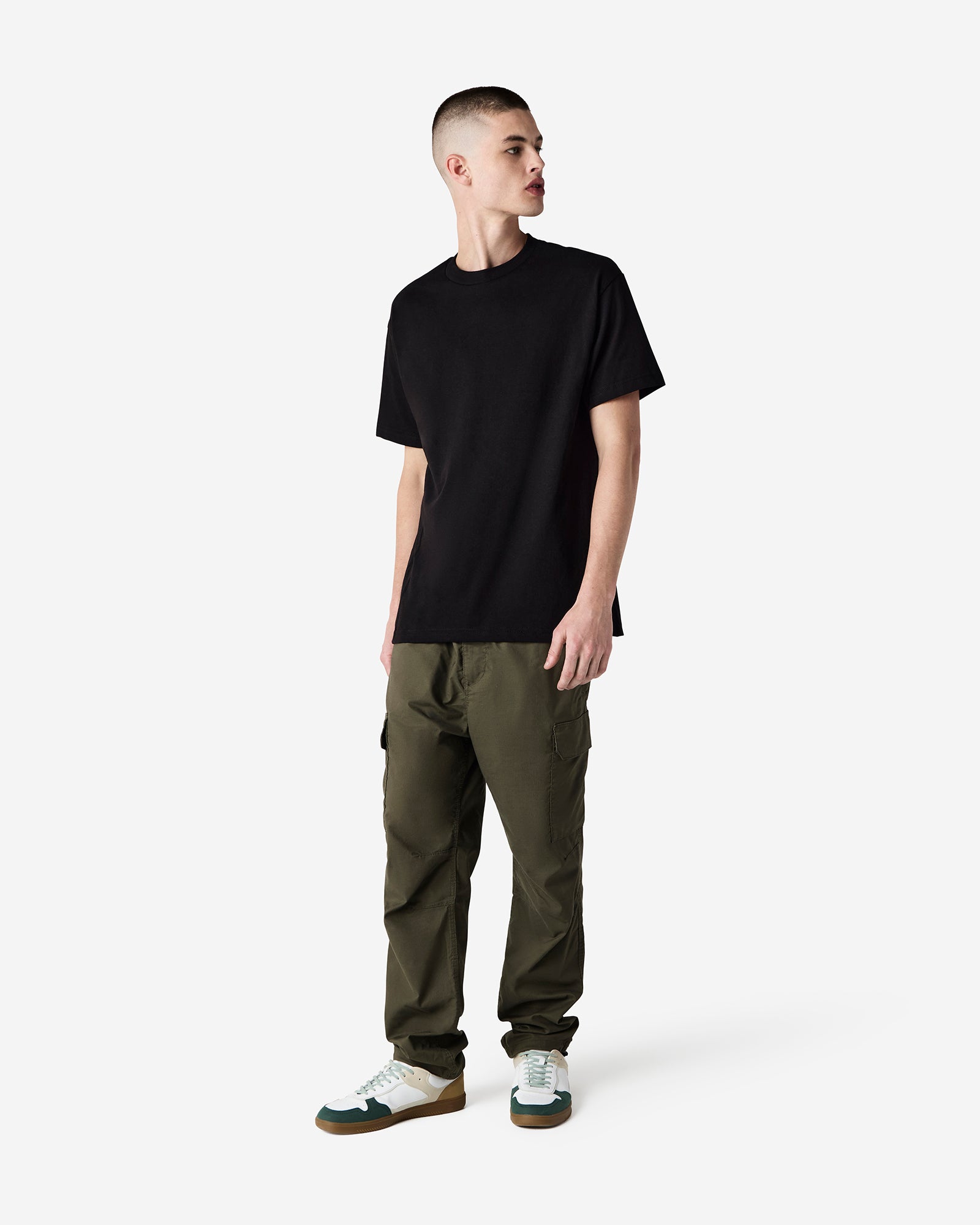 Male Model wearing a Black Heavyweight Unisex short Sleeve Crew Neck Tee, paired with brown jeans, standing against a plain background (front pose) -black
