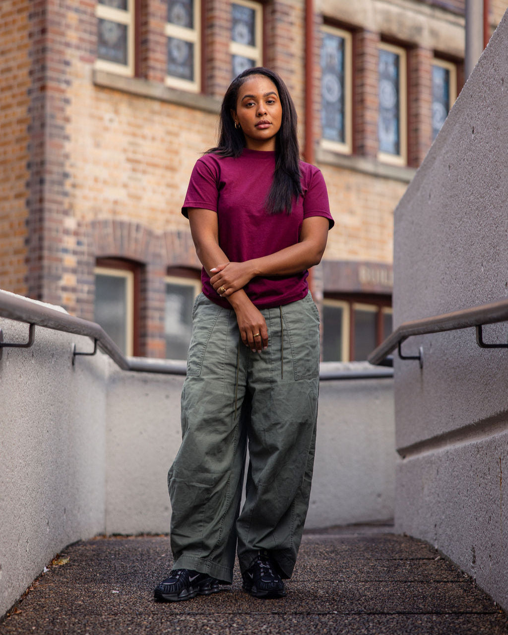 Female Model wearing a Burgundy Heavyweight Unisex Short Sleeve Crew Neck Tee, paired with blue jeans, standing against a plain background (front pose) -burgundy