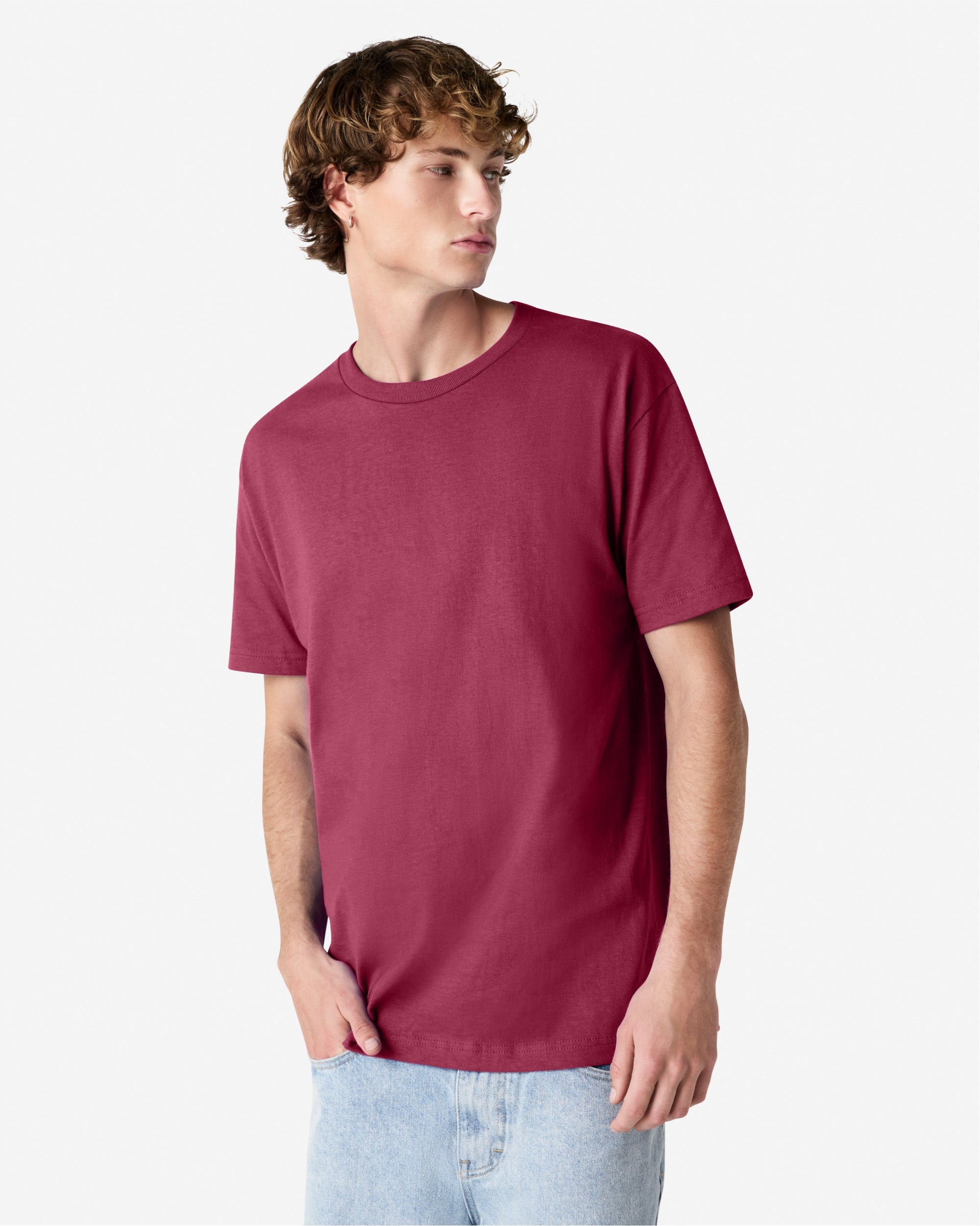 Male Model wearing a Burgundy Heavyweight Unisex Short Sleeve Crew Neck Tee, paired with blue jeans, standing against a plain background (front pose) -burgundy