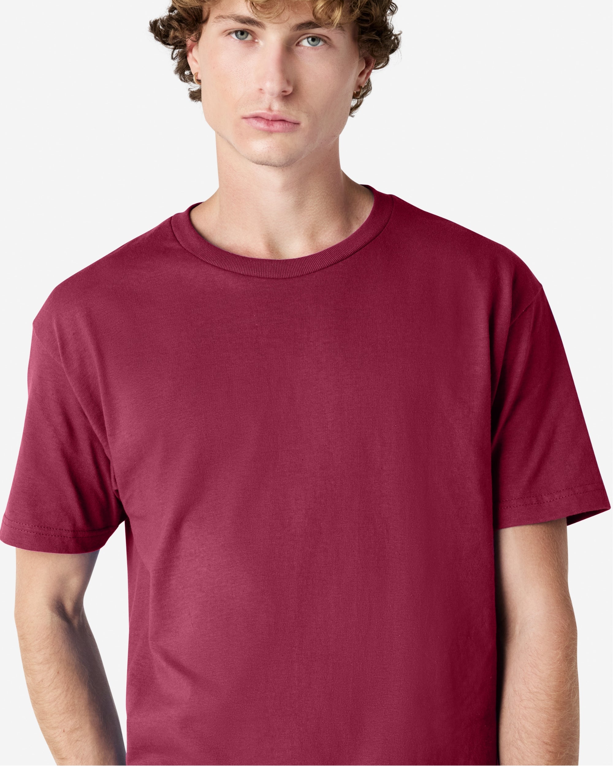 Male Model wearing a Burgundy Heavyweight Unisex Short Sleeve Crew Neck Tee, paired with blue jeans, standing against a plain background (front pose) -burgundy