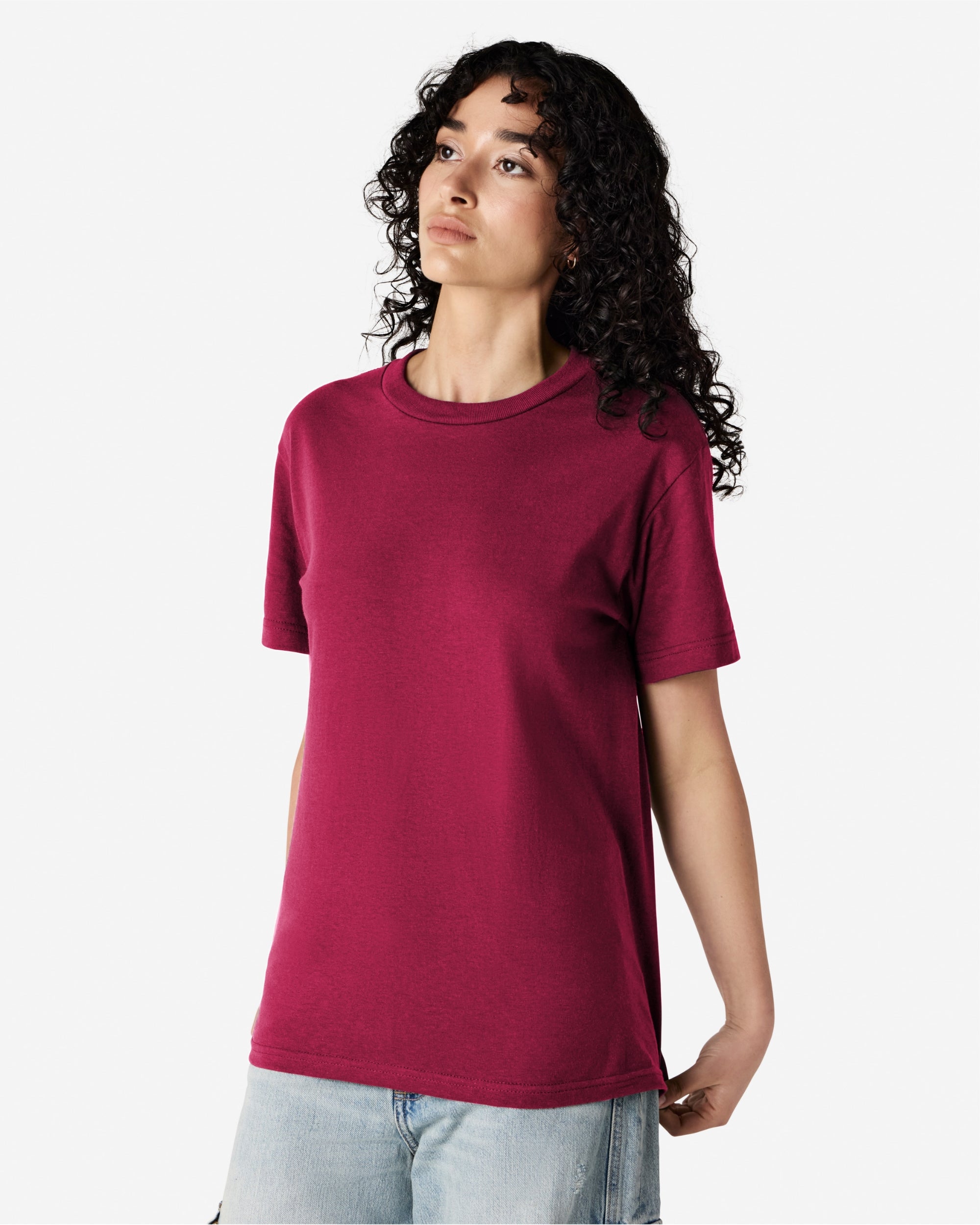 Female Model wearing a Burgundy Heavyweight Unisex Short Sleeve Crew Neck Tee, paired with blue jeans, standing against a plain background (front pose) -burgundy