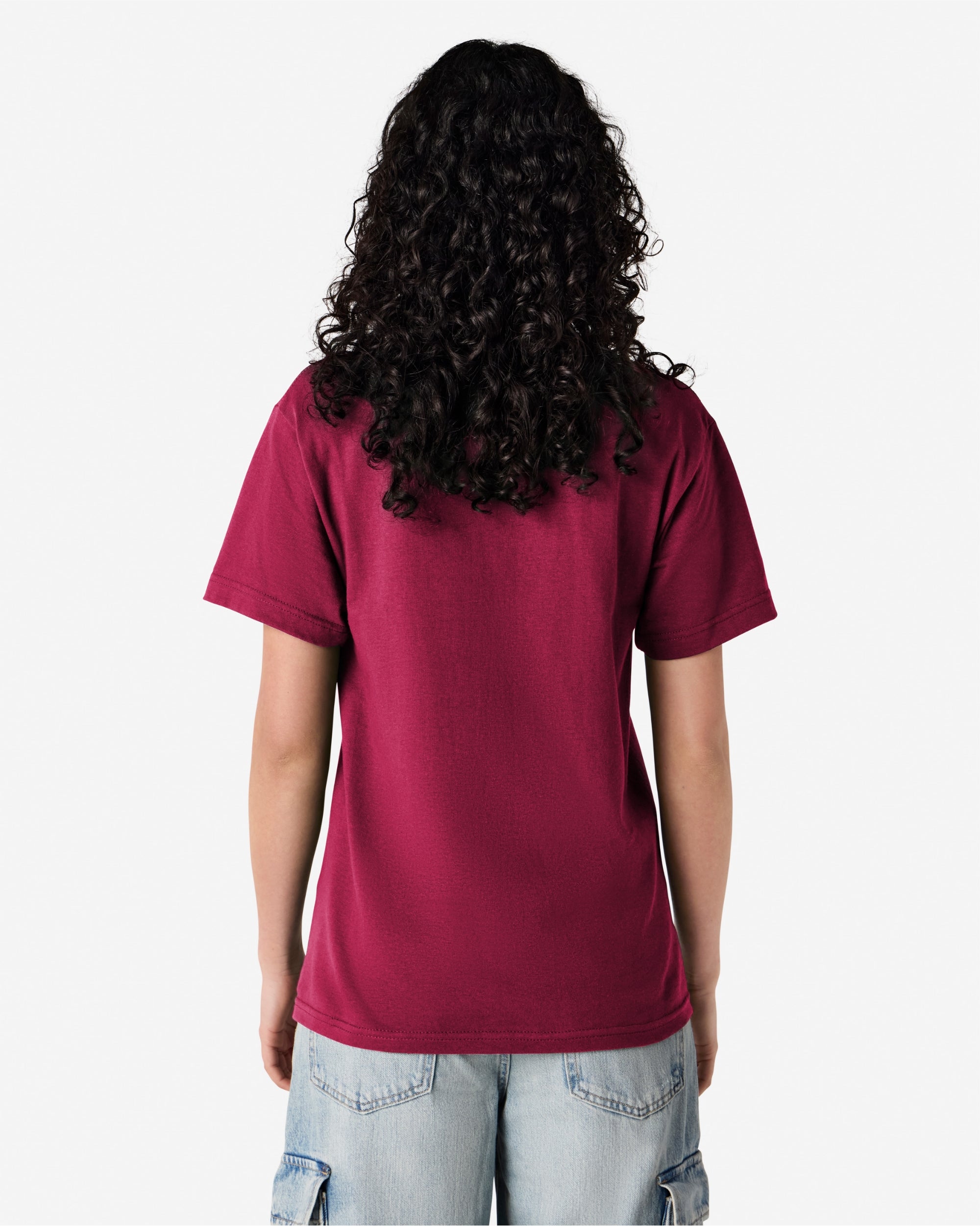 Female Model wearing a Burgundy Heavyweight Unisex Short Sleeve Crew Neck Tee, paired with blue jeans, standing against a plain background (back pose) -burgundy