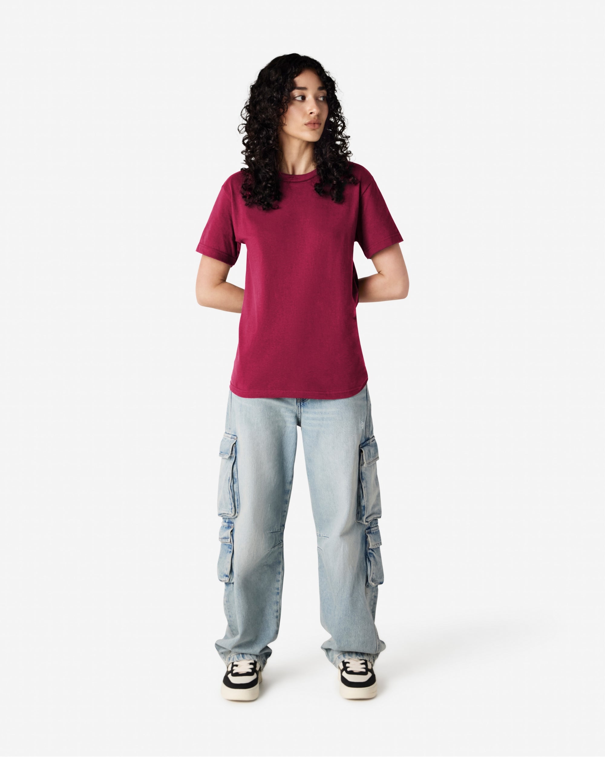 Female Model wearing a Burgundy Heavyweight Unisex Short Sleeve Crew Neck Tee, paired with blue jeans, standing against a plain background (front pose) -burgundy