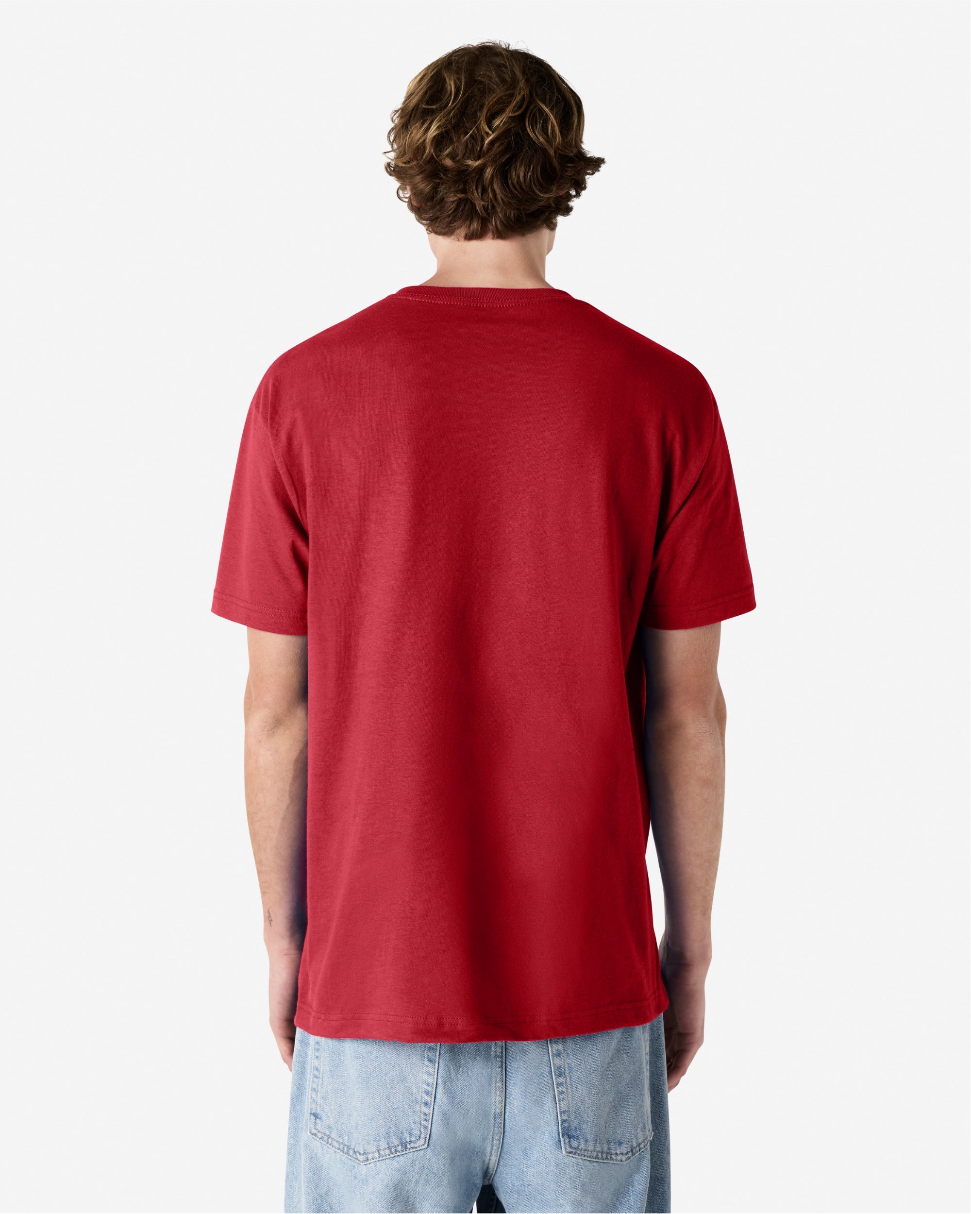 Male Model wearing a Cardinal Heavyweight Unisex Short Sleeve Crew Neck Tee, paired with blue jeans, standing against a plain background (back pose) -cardinal red
