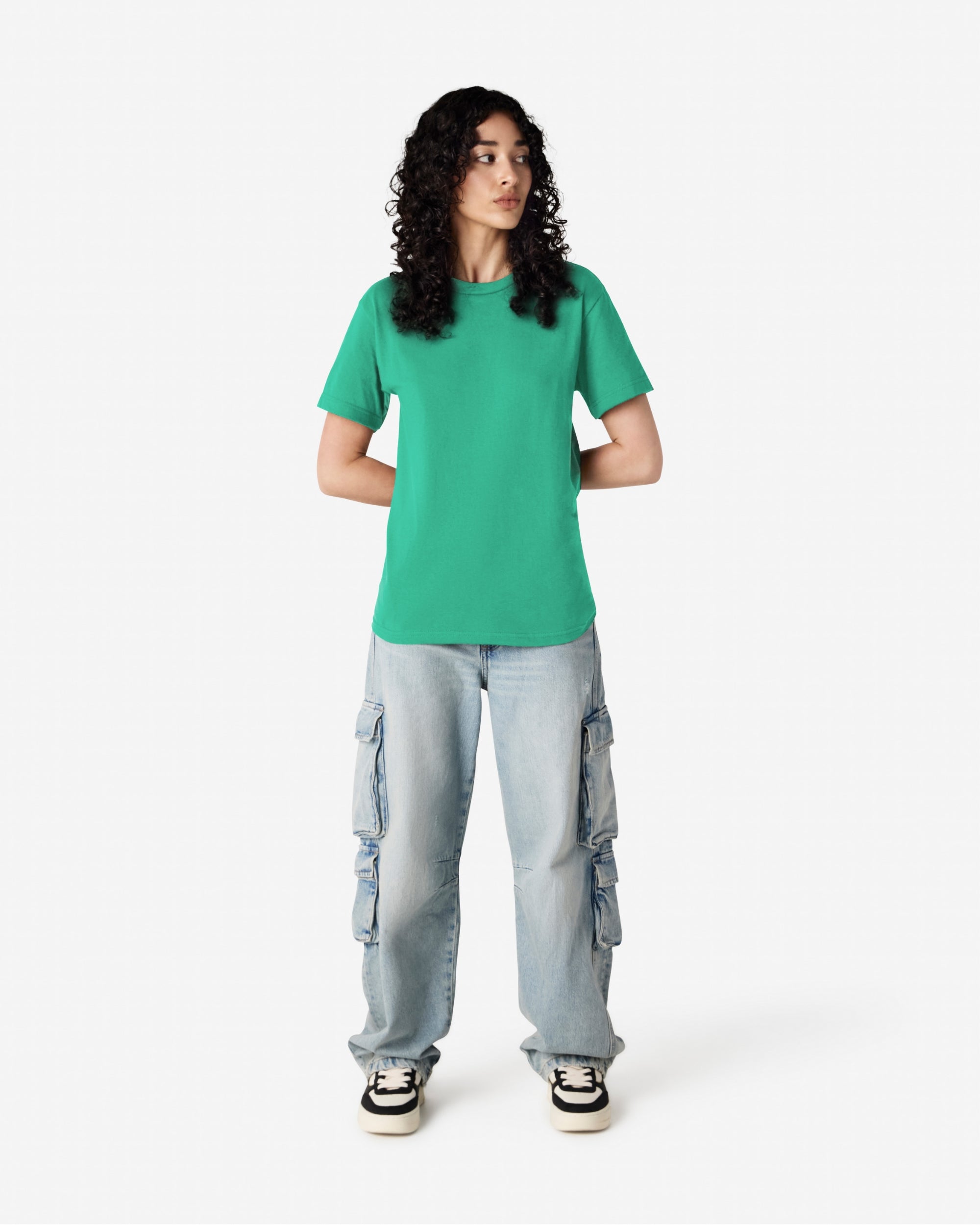 Female Model wearing a Celadon Heavyweight Unisex Short Sleeve Crew Neck Tee, paired with blue jeans, standing against a plain background (front pose) -celadon