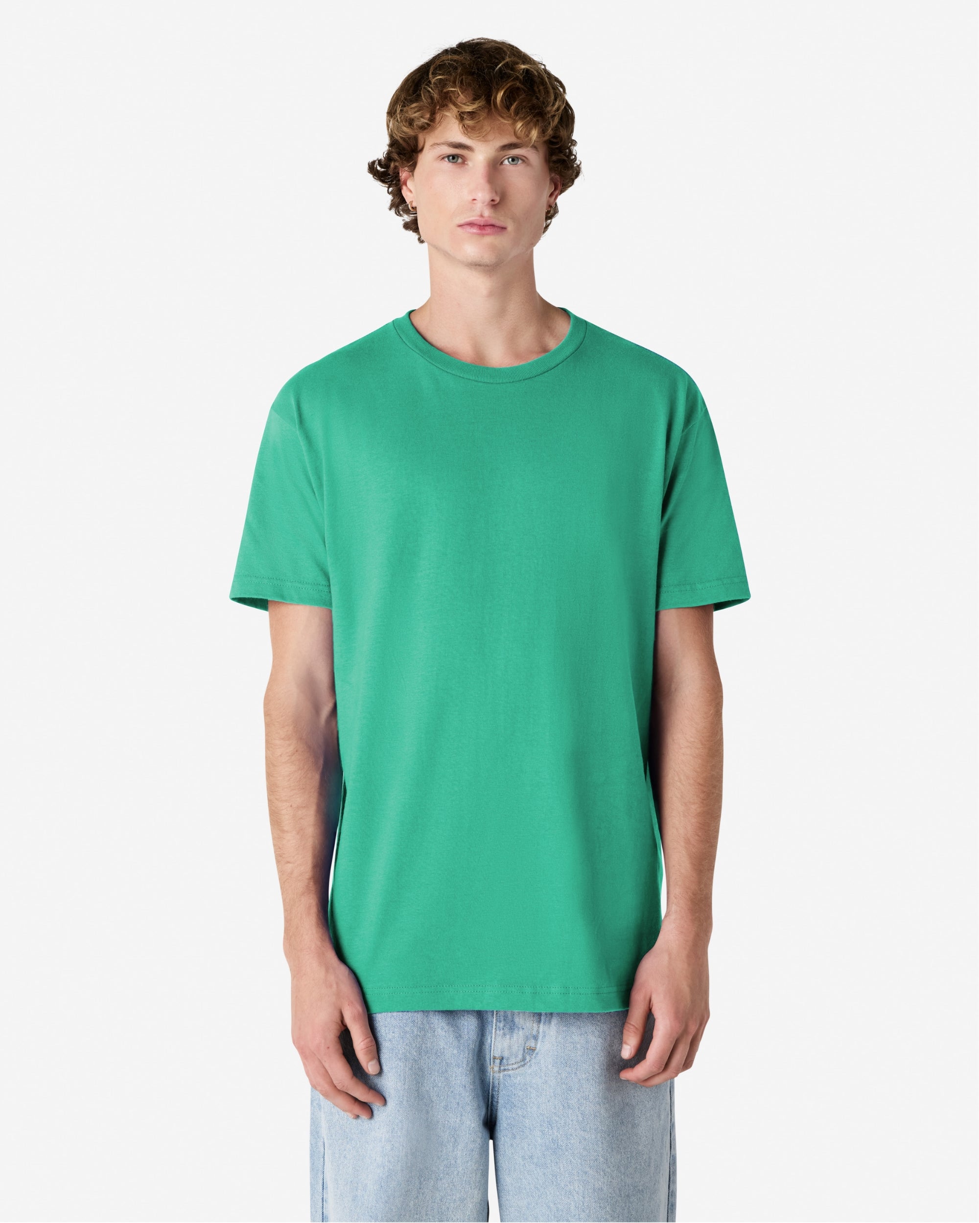 Male Model wearing a Celadon Heavyweight Unisex Short Sleeve Crew Neck Tee, paired with blue jeans, standing against a plain background (front pose) -celadon