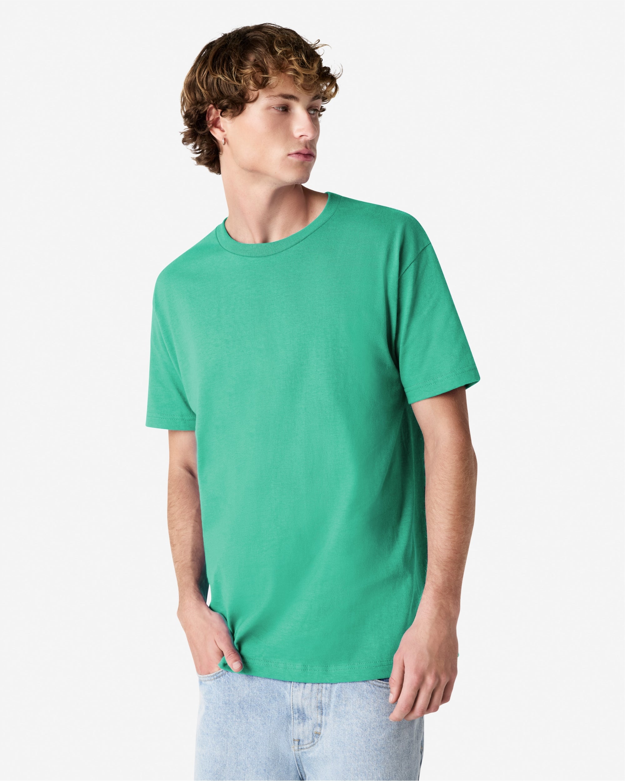 Male Model wearing a Celadon Heavyweight Unisex Short Sleeve Crew Neck Tee, paired with blue jeans, standing against a plain background (front pose) -celadon