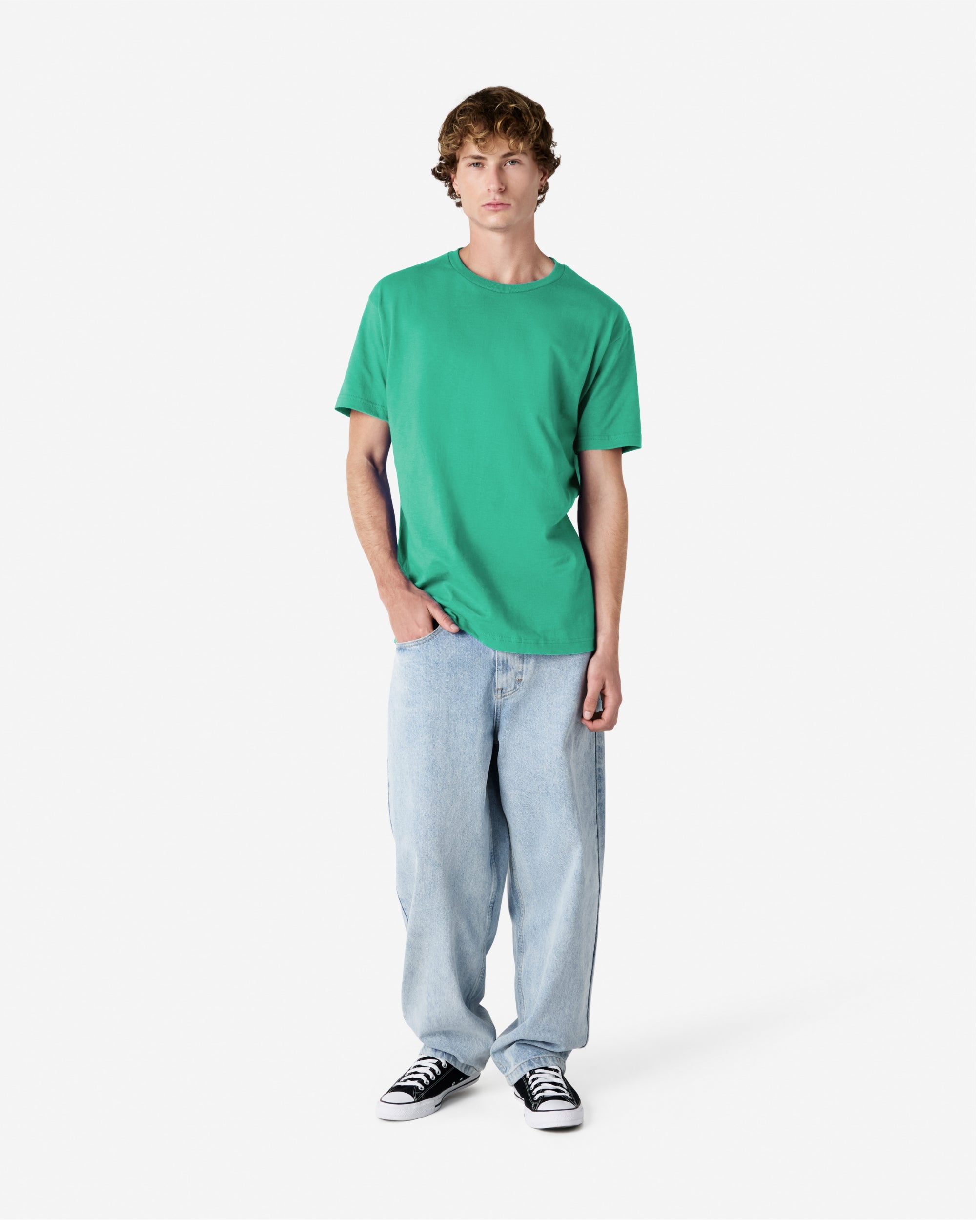 Male Model wearing a Celadon Heavyweight Unisex Short Sleeve Crew Neck Tee, paired with blue jeans, standing against a plain background (front pose) -celadon
