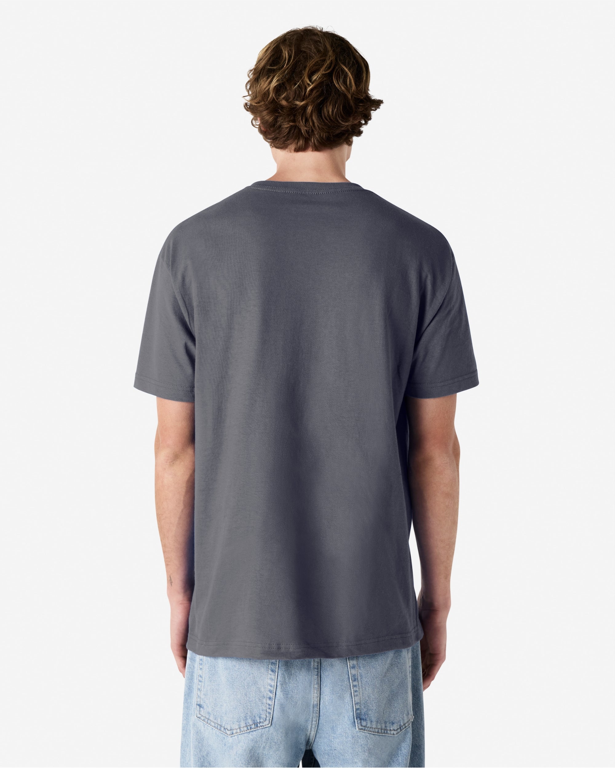 Male Model wearing a Charcoal Heavyweight Unisex Short Sleeve Crew Neck Tee, paired with blue jeans, standing against a plain background (back pose) -charcoal