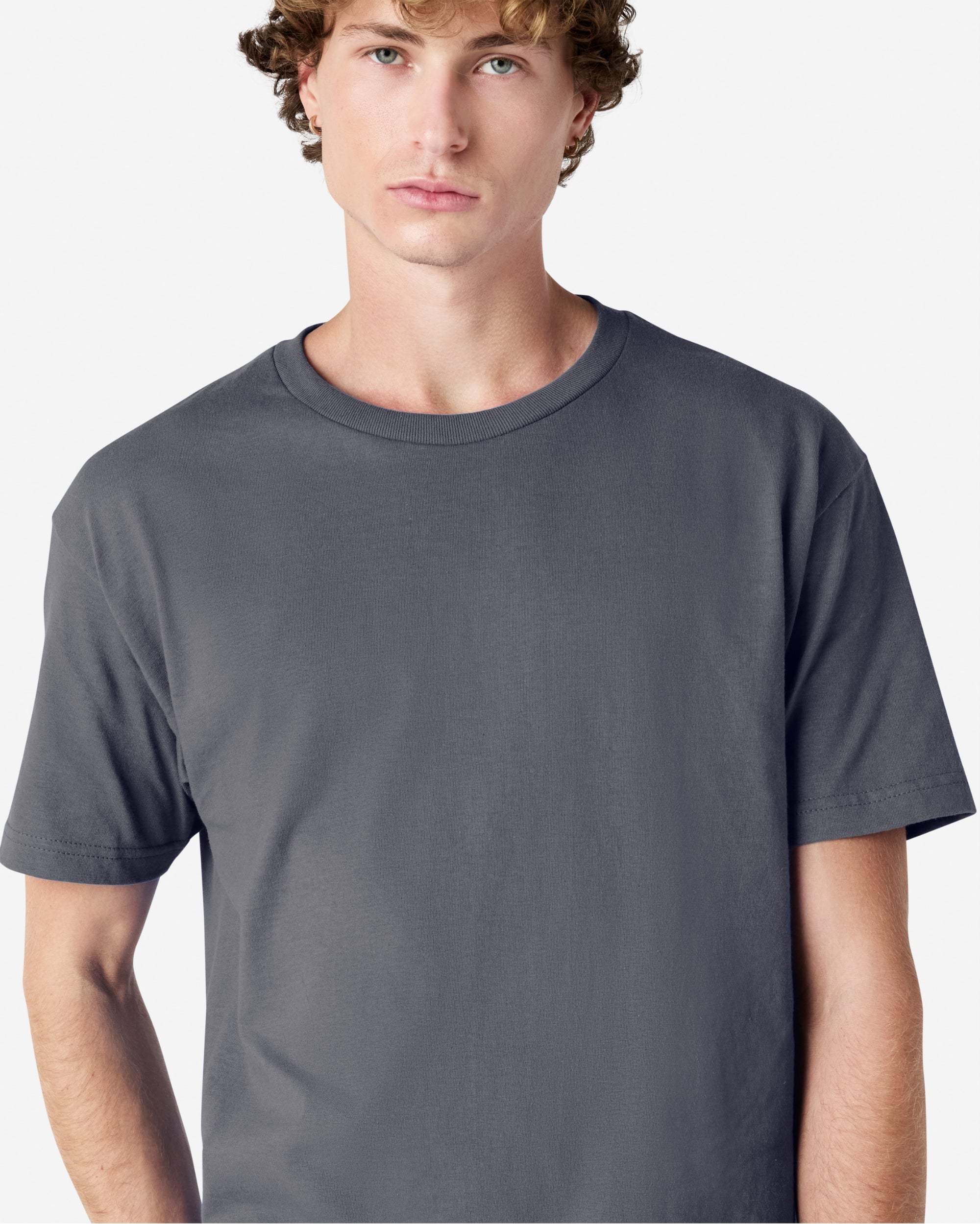Male Model wearing a Charcoal Heavyweight Unisex Short Sleeve Crew Neck Tee, paired with blue jeans, standing against a plain background (front pose) -charcoal